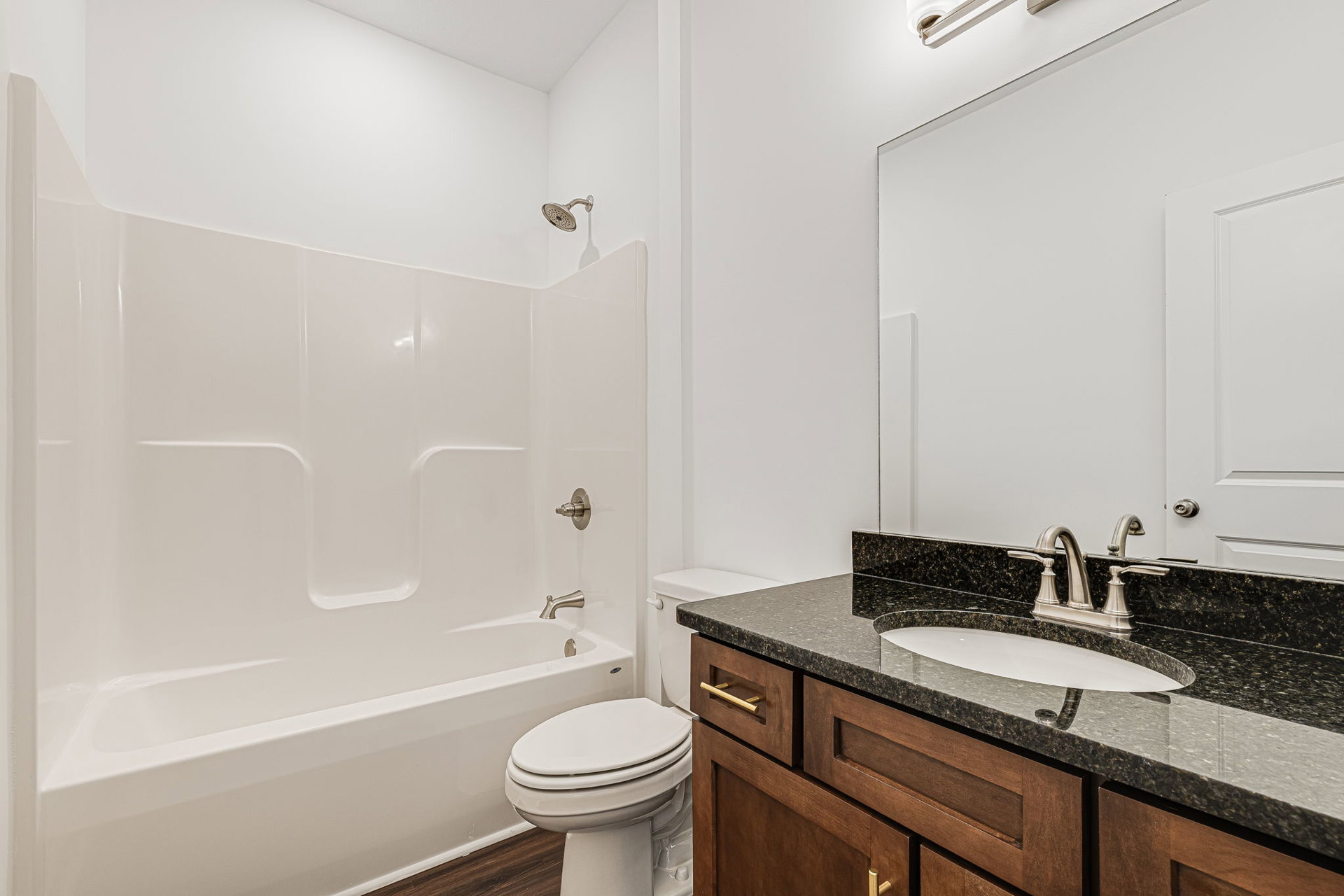 Modern bathroom featuring a freestanding bathtub, white ceramic sink with chrome faucet, wall-mounted mirror, tiled walls, and a closed white toilet.