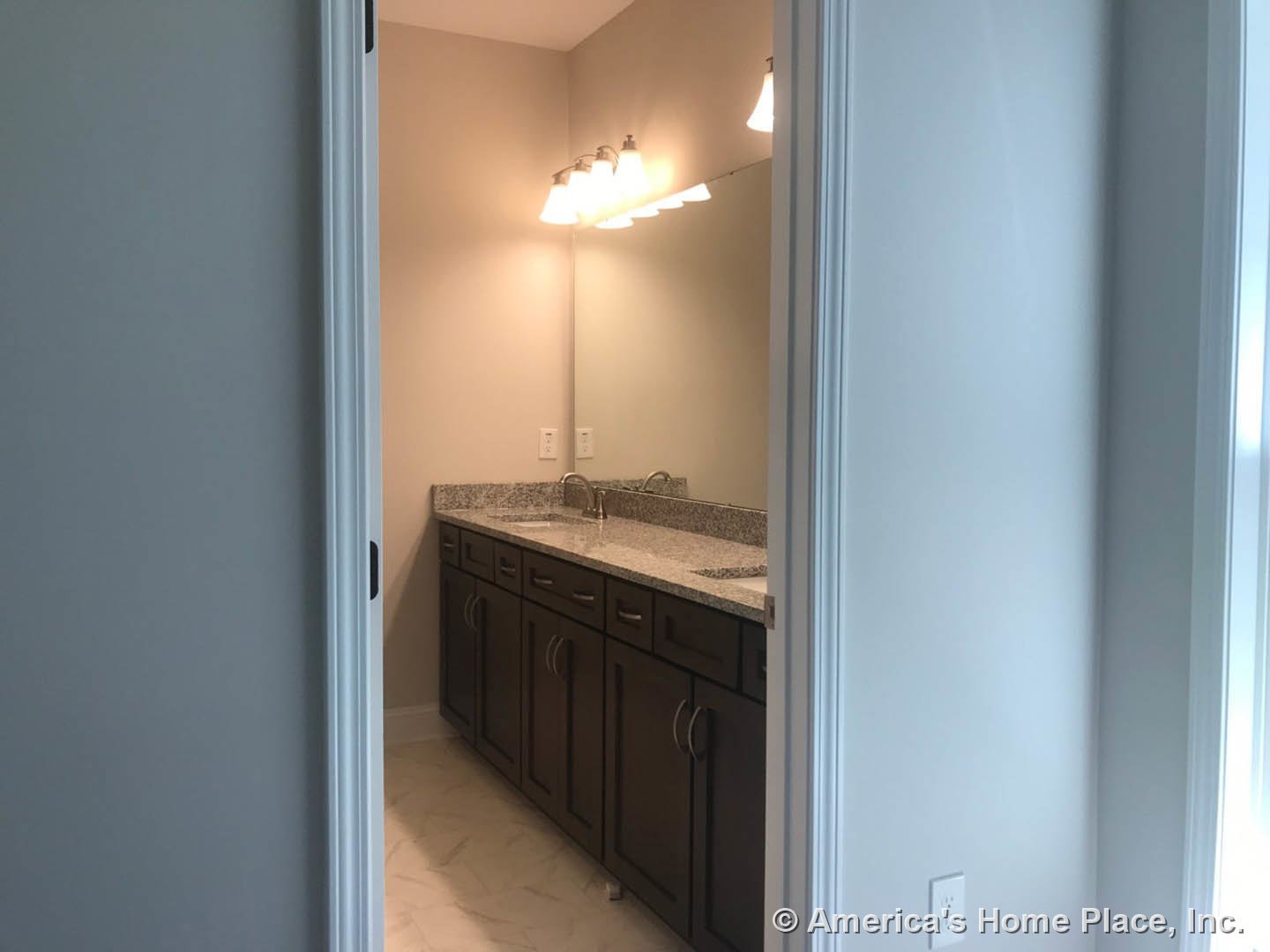 Bathroom with granite countertop, undermount sink, wall-mounted mirror, white tile flooring, white outlet, and recessed lighting on white walls.