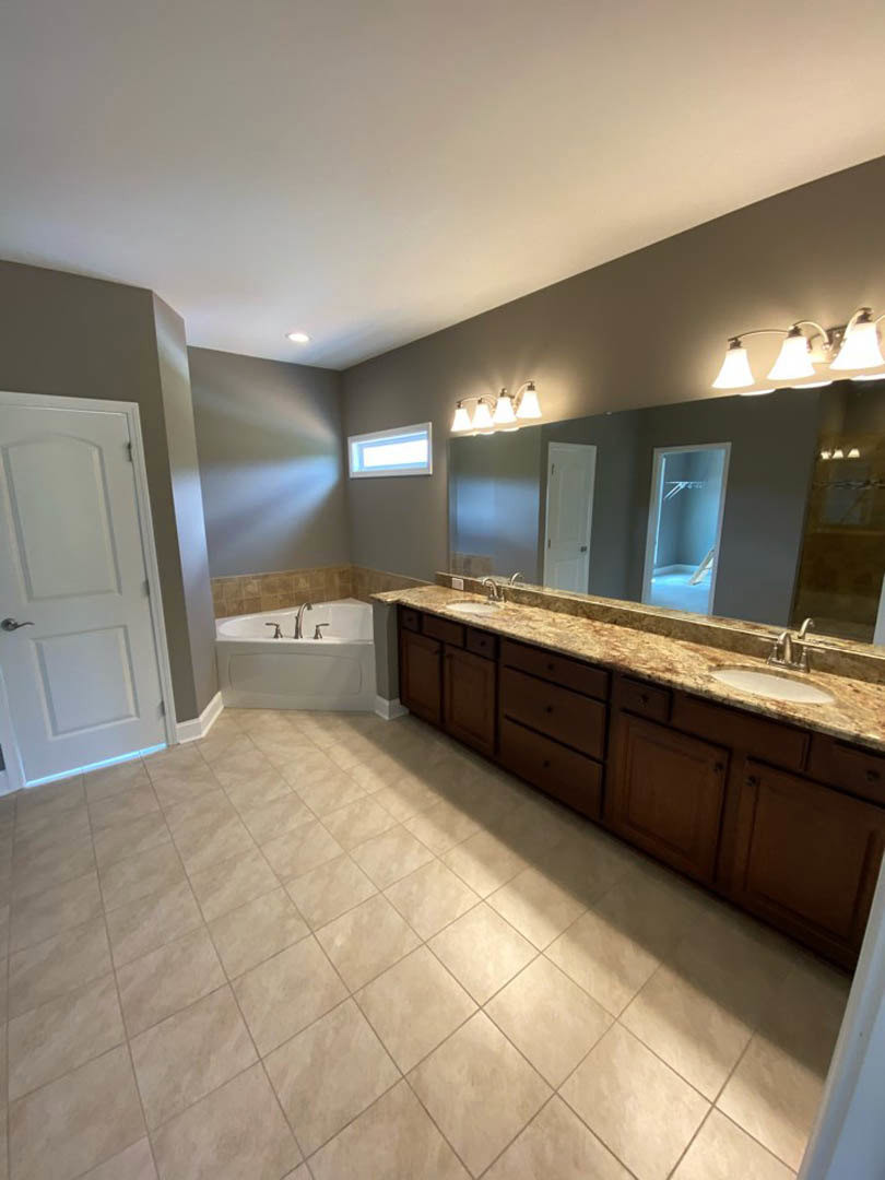Bathroom featuring a marble countertop, freestanding tub, white door with silver handle, tile flooring, and modern light fixture