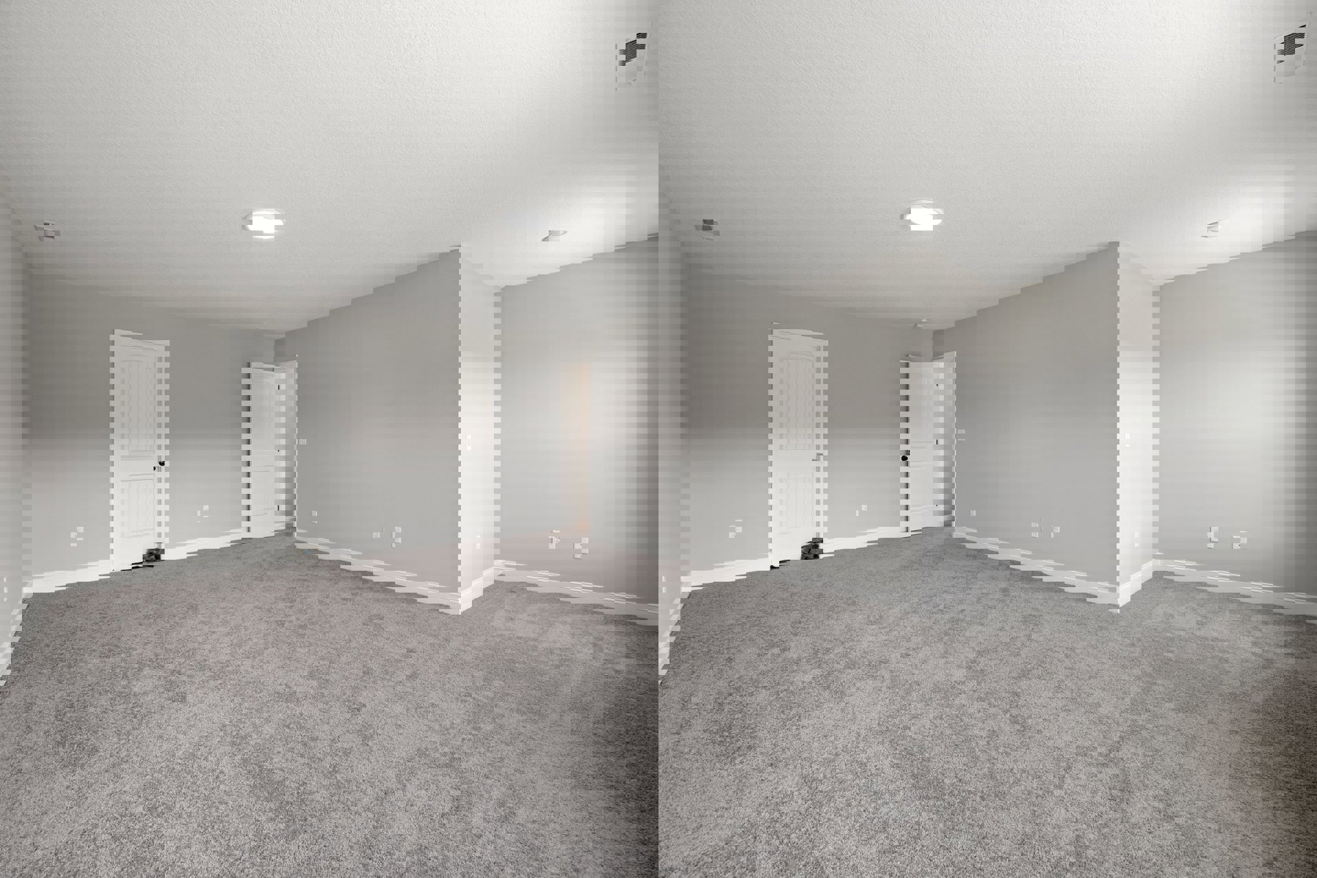 Grey carpeted room with white walls, white door featuring black handle and knobs, round ceiling light fixture on white ceiling