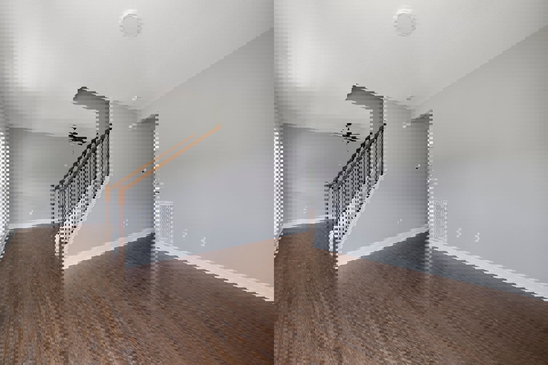 Open living area with hardwood floors, white plaster walls, wooden staircase with white railing, ceiling fan with light fixture, and recessed lighting.