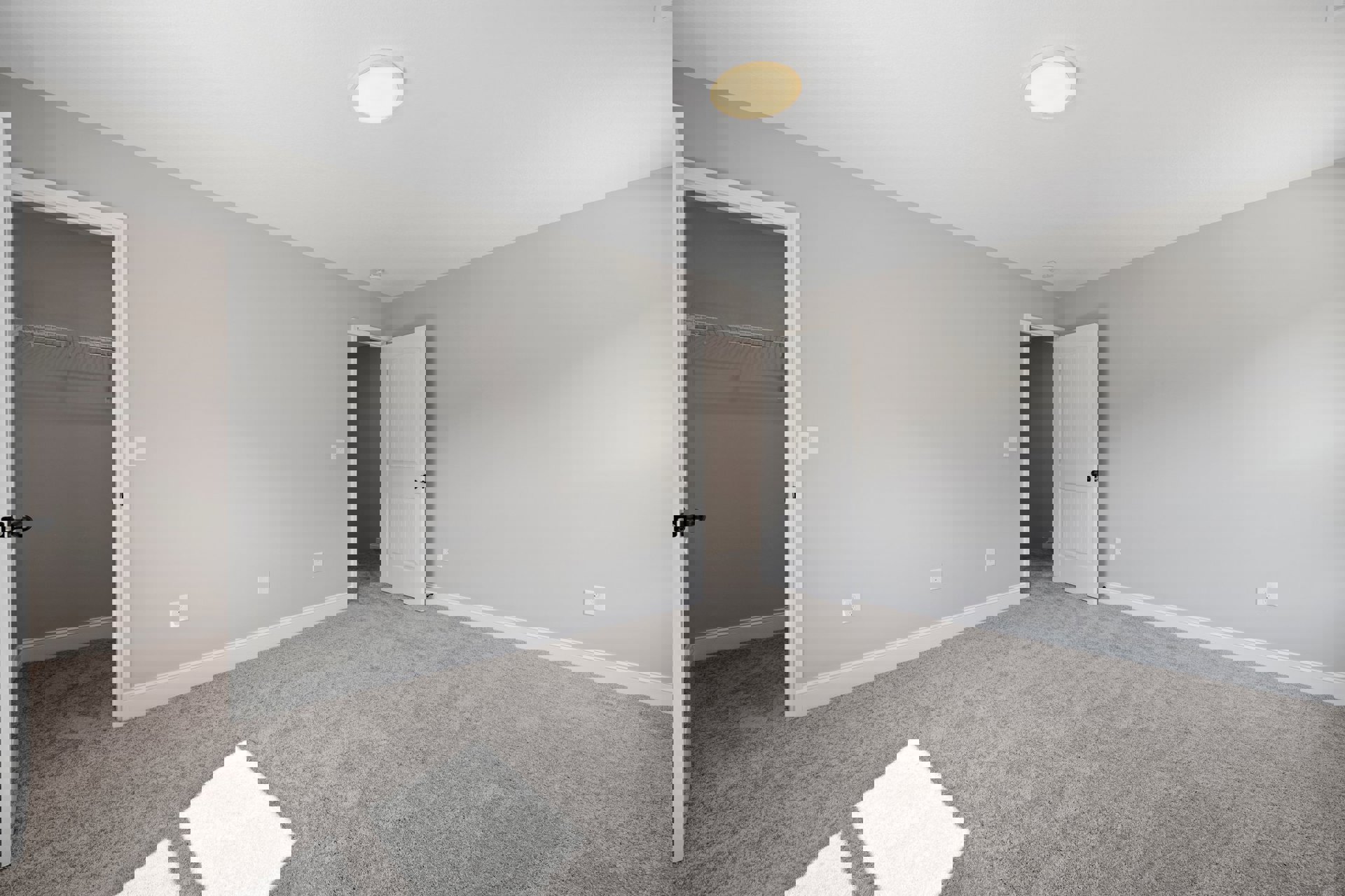 Carpeted bedroom with white walls, open white door with black knob, ceiling light fixture, closet with white interior