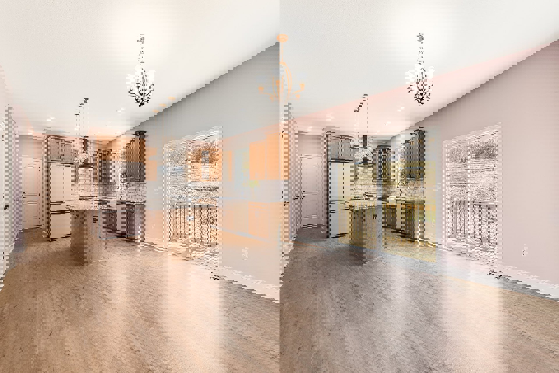 Open kitchen and living room featuring white cabinets, hardwood flooring, sliding glass door with black handles, outdoor fence visible, and chandelier lighting