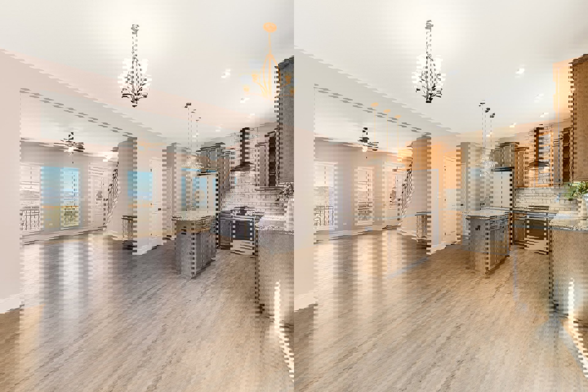 Spacious open floor plan featuring a central kitchen island, wood flooring, modern cabinetry, chandelier lighting, stainless steel stove with glass door, and large windows offering