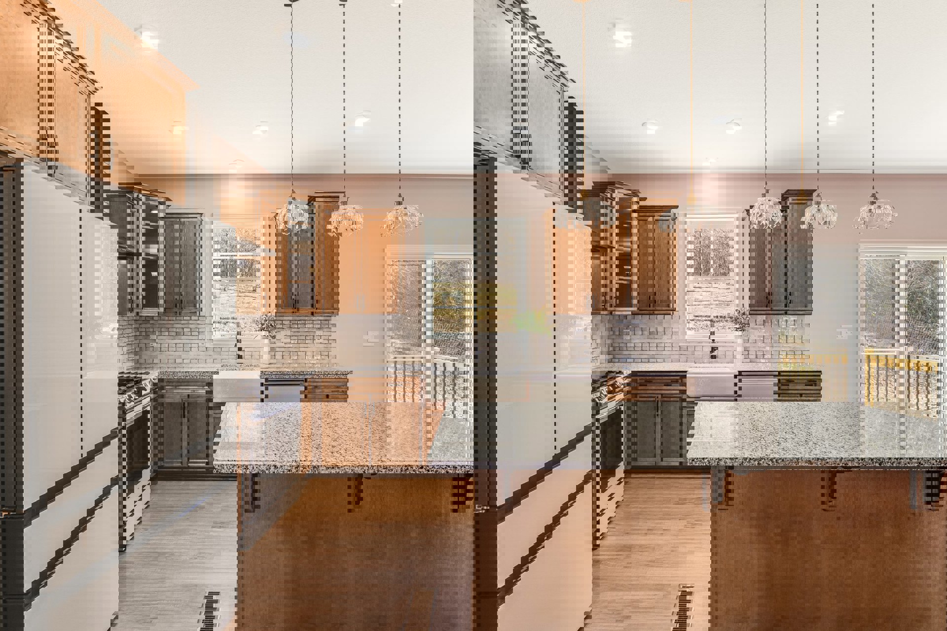 Marble kitchen countertop with black speckled surface, white cabinets with black trim, white oven with glass door, window overlooking field and trees