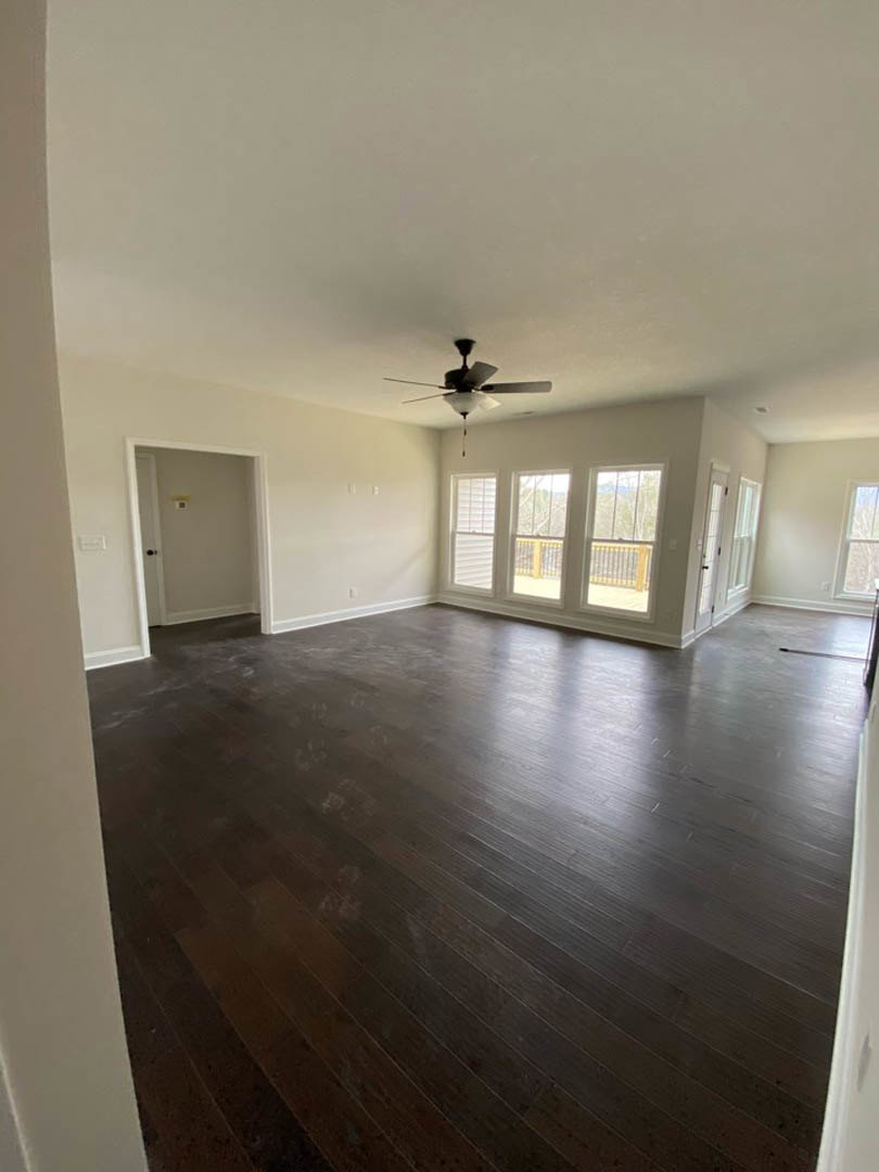 Ceiling fan with light fixture, hardwood floors, white door with light switch, window featuring railing, neutral walls and trim