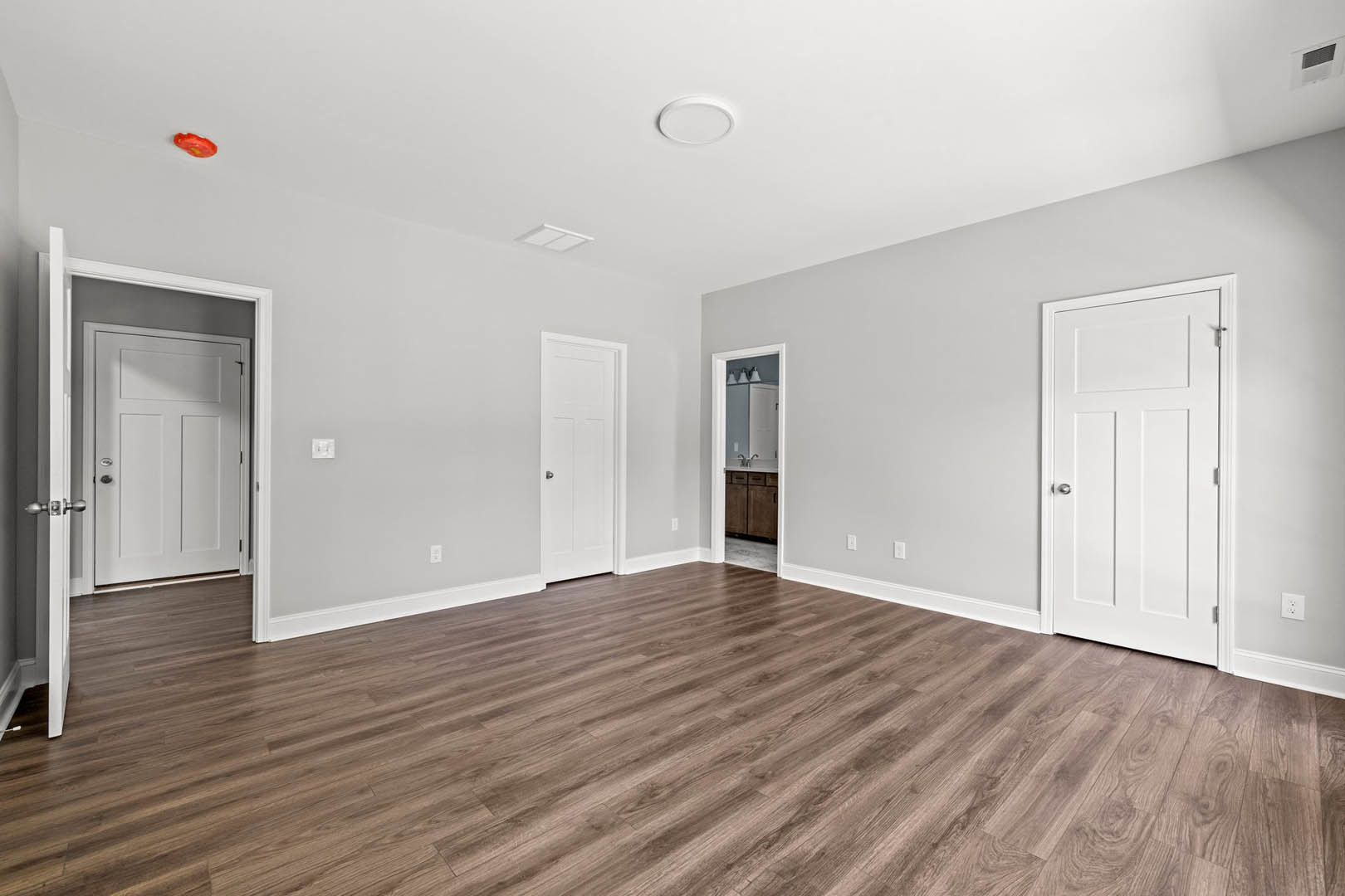 White walls and ceiling, open white door with silver knob, hardwood floor, minimal trim detailing