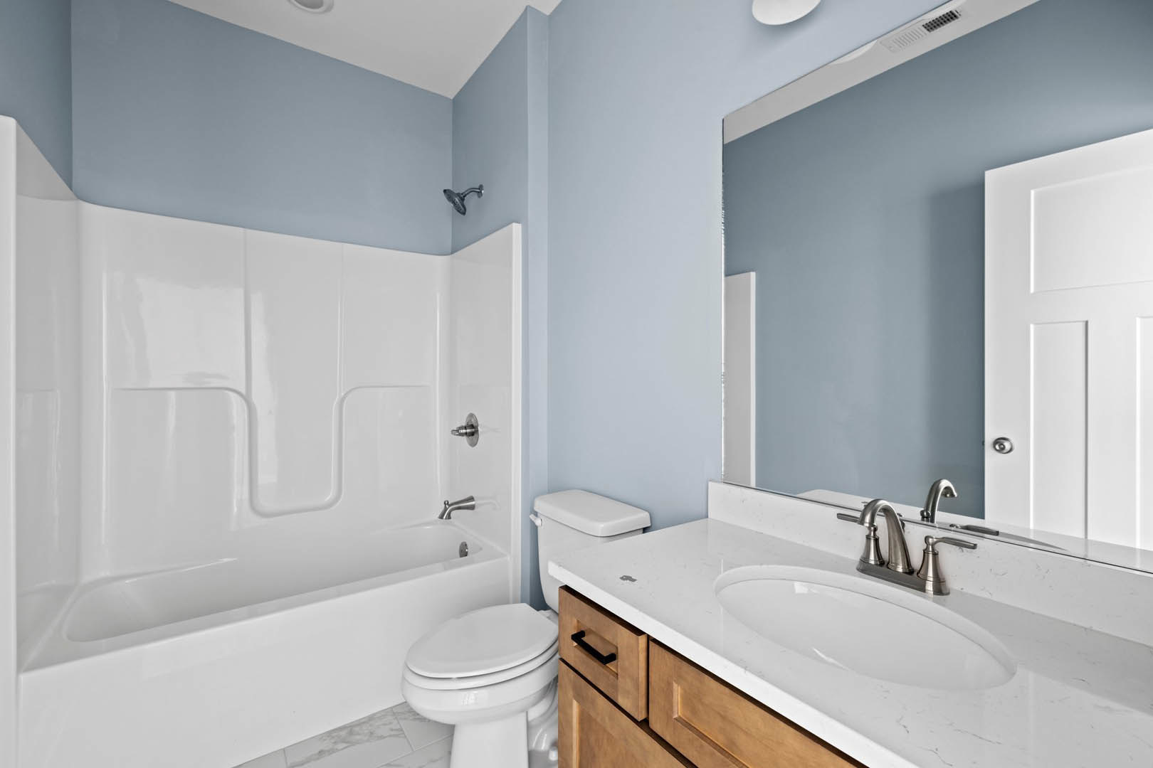 White bathtub, pedestal sink, and toilet in a bathroom with light tile walls and chrome fixtures