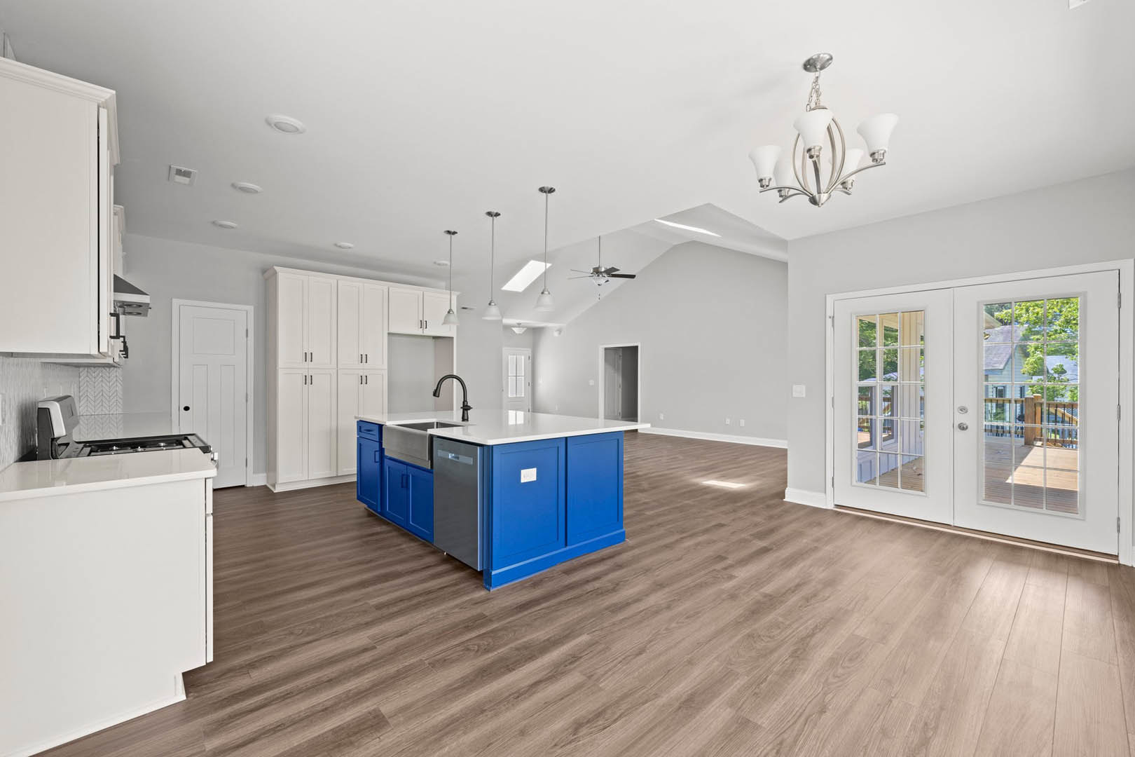 Blue kitchen cabinets with stainless steel dishwasher, wood flooring, double glass-paneled doors, white-shaded light fixture, and a door with a glass window.