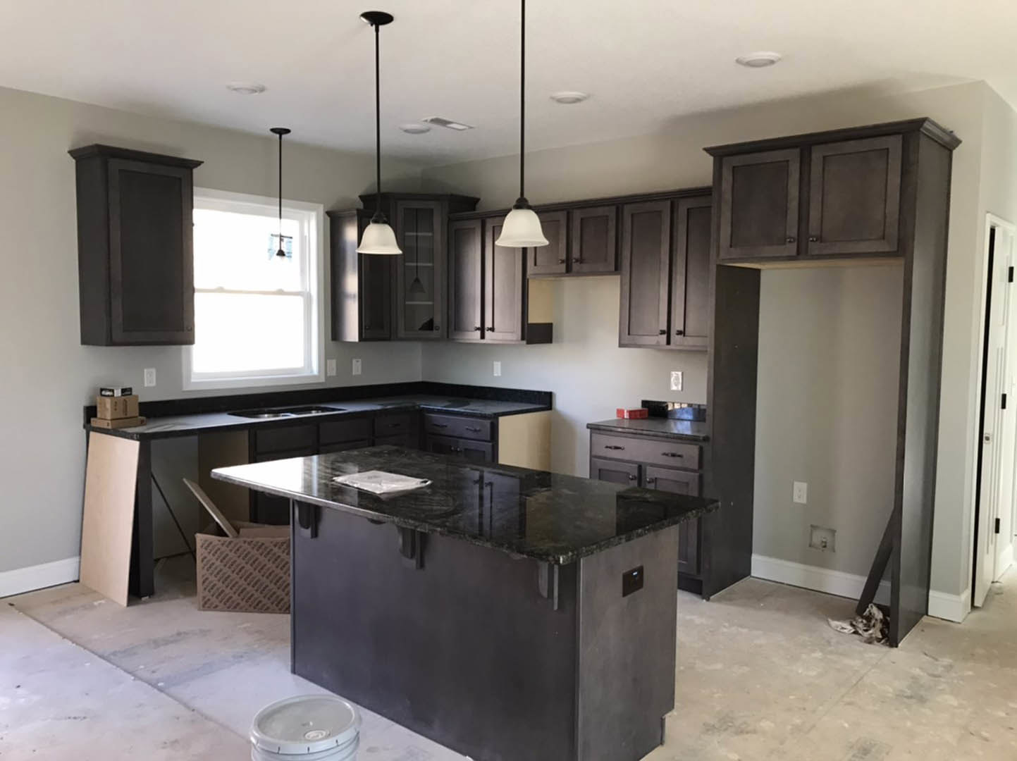Kitchen featuring dark wood cabinets, matte black countertop, stainless steel appliances, undermount sink, and large window providing natural light.