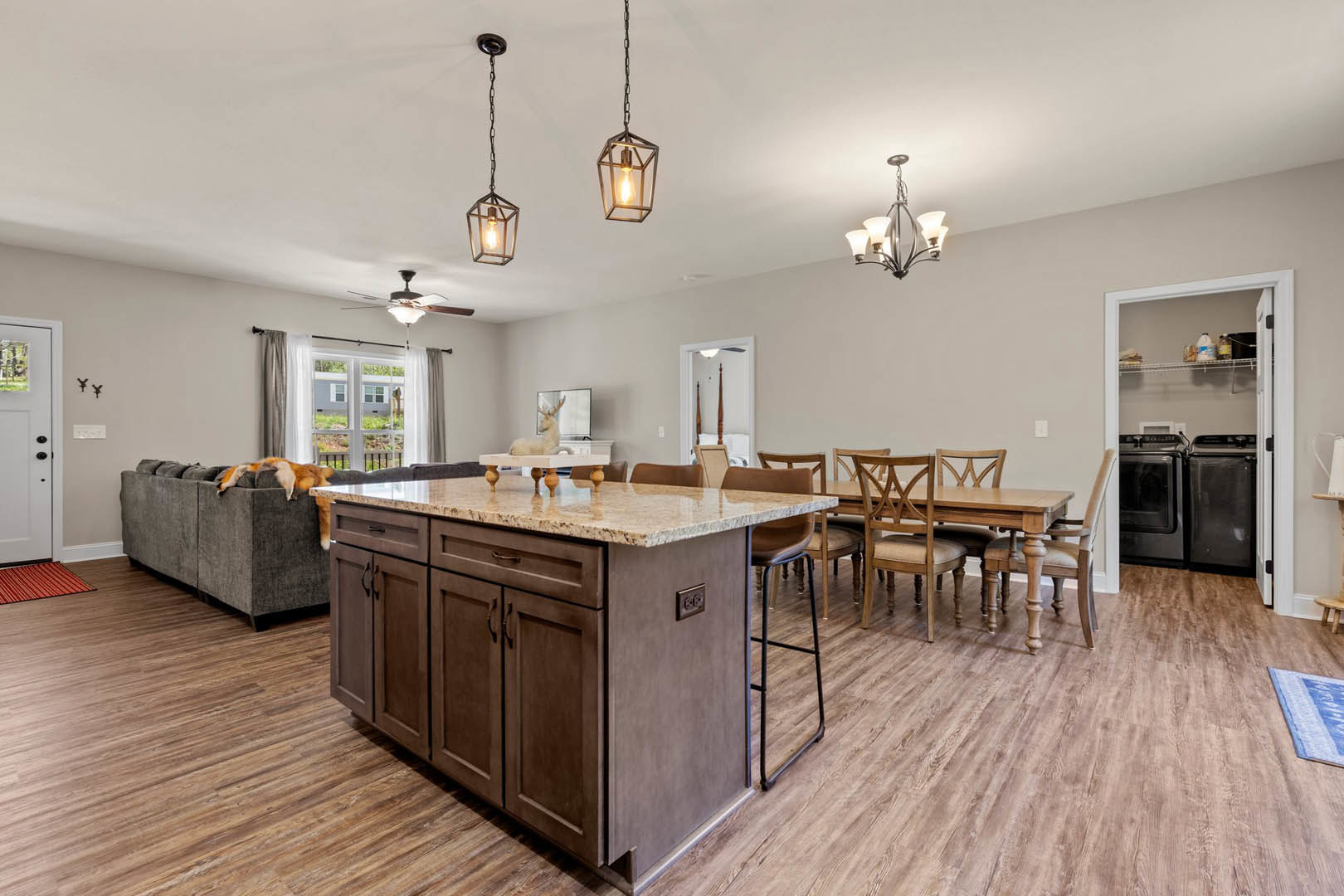 Open kitchen and dining area featuring a marble-topped island, wood cabinetry, stainless steel sink, dining table with chairs, chandelier suspended by chain, closet door, large