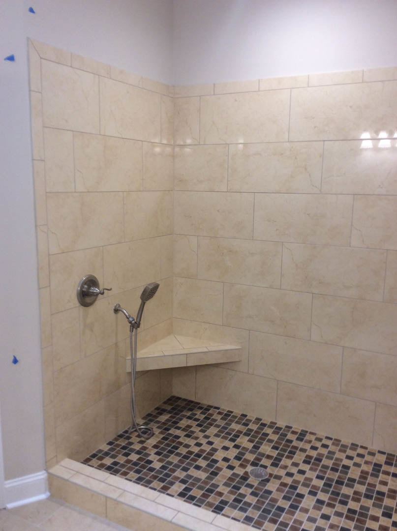 Walk-in shower with dual chrome shower heads, white marble tile walls, tile floor with central drain, and visible metal plumbing fixtures