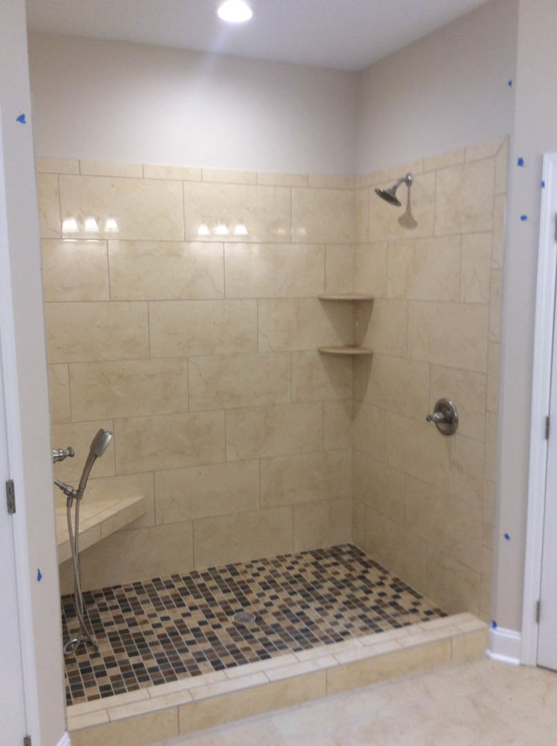 Walk-in shower with two chrome shower heads, white tile walls, and a tiled floor with central drain