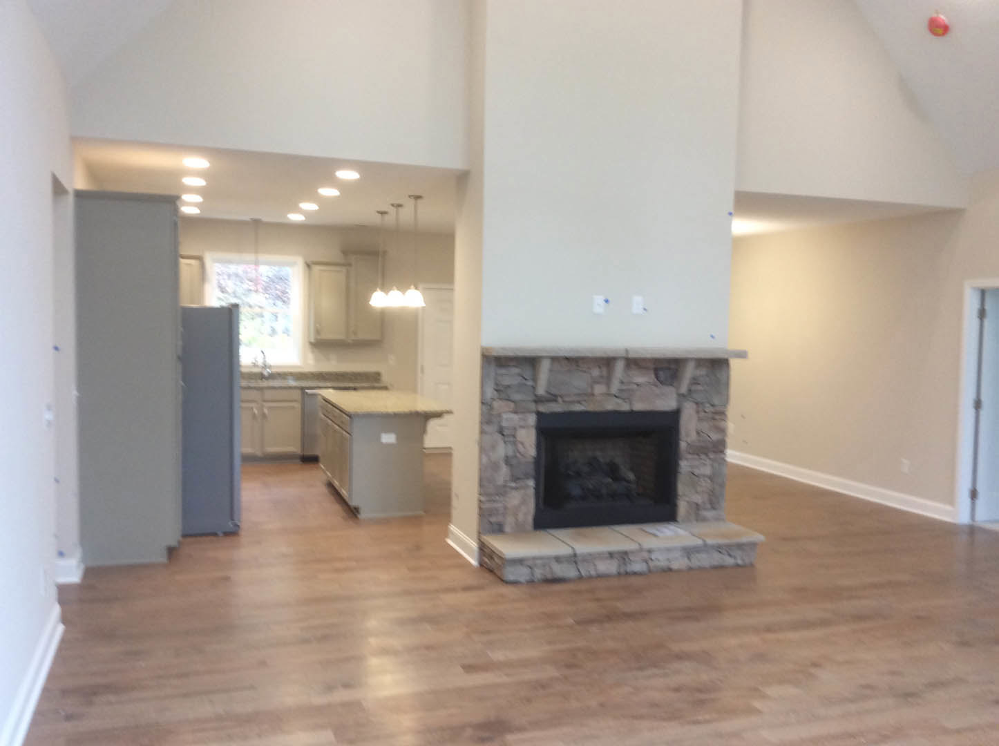 Stone fireplace with white plaster wall, wood flooring, and hearth in living room