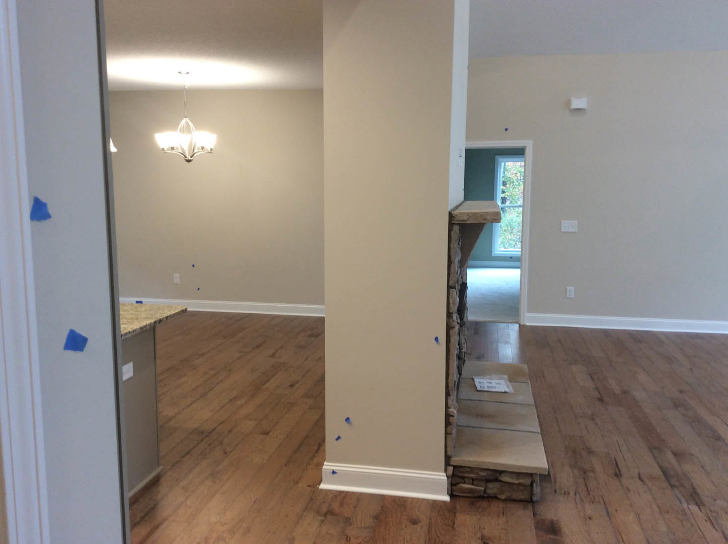 Living room with wood flooring, white walls, blue accent wall, modern fireplace, and three-shade chandelier