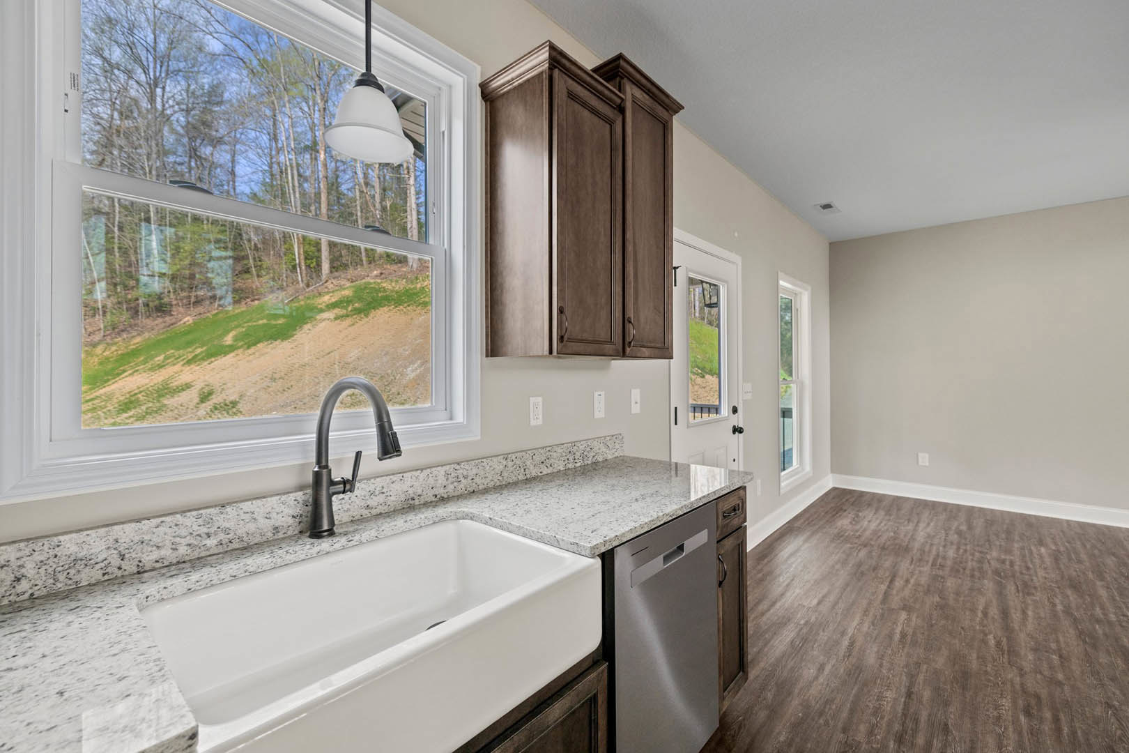 Modern kitchen featuring a white undermount sink with chrome faucet, stainless steel dishwasher, brown cabinetry, white tile backsplash, and recessed lighting