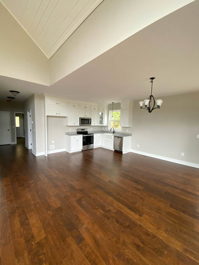 Spacious empty room with light hardwood floors, white walls, and recessed ceiling lights