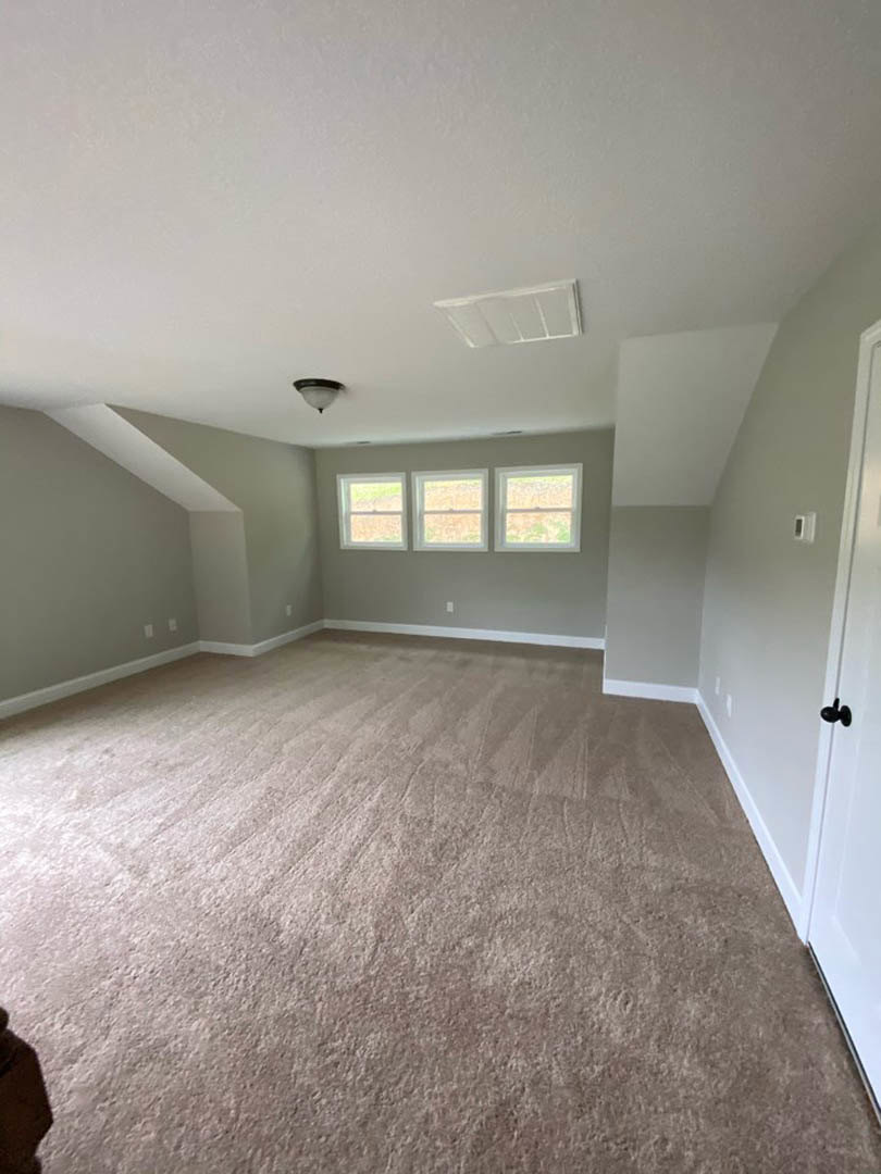 Carpeted room with white-trimmed windows, white door, and light-colored walls