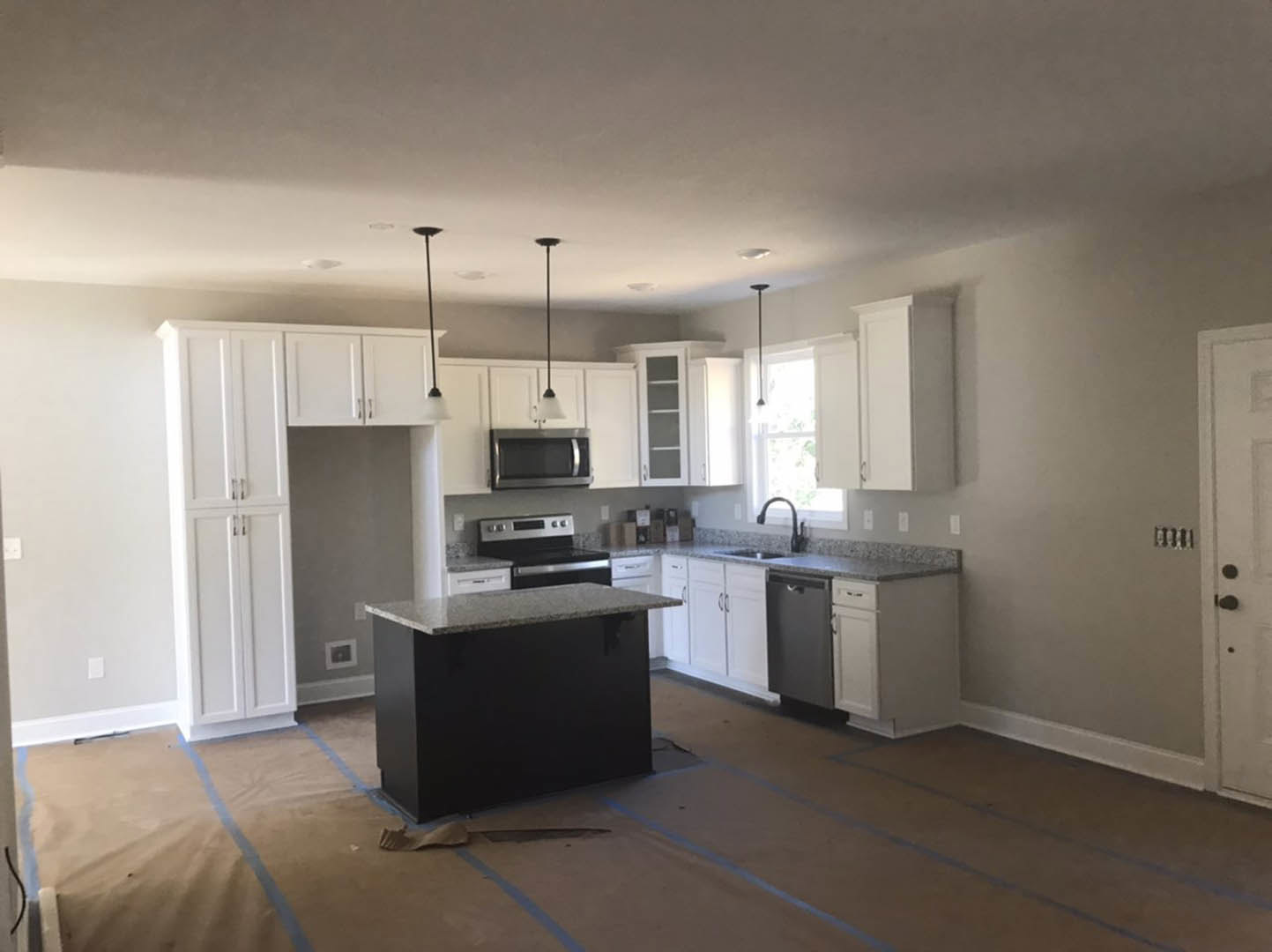 White kitchen cabinets with black island, quartz countertops, stainless steel appliances, light wood flooring, and recessed lighting