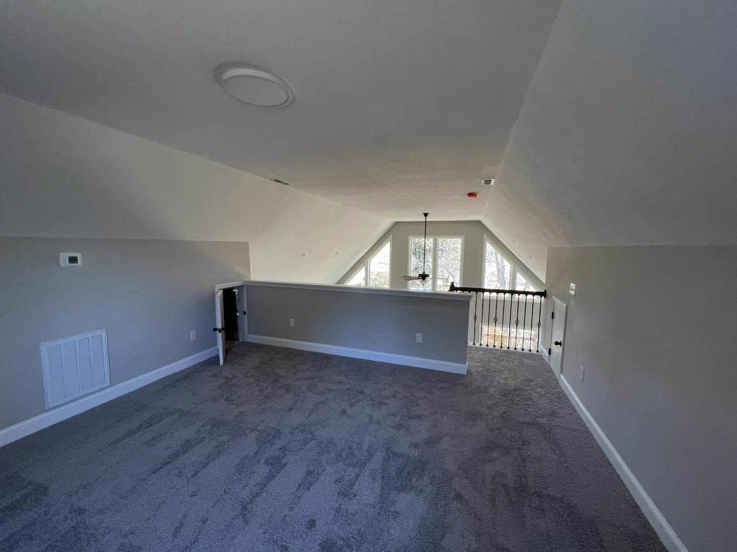 Carpeted room with white walls, open door, window, and close-up of white air filter and railing