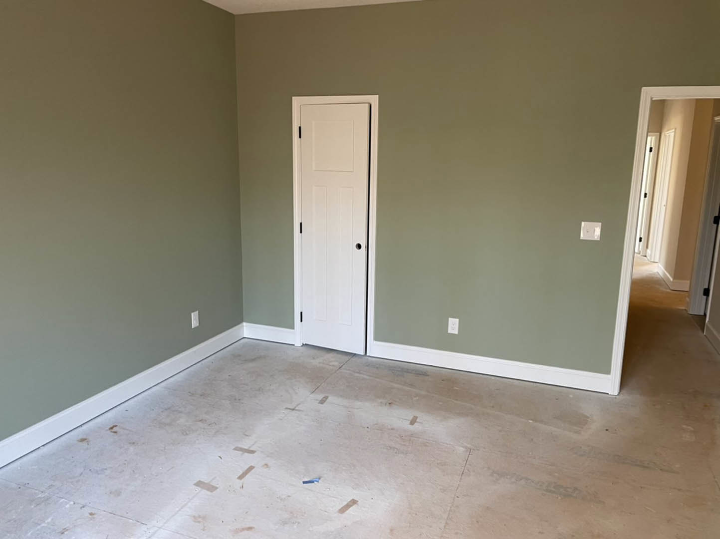 White paneled door with round hole, adjacent to smooth white wall and tiled floor marked with tape