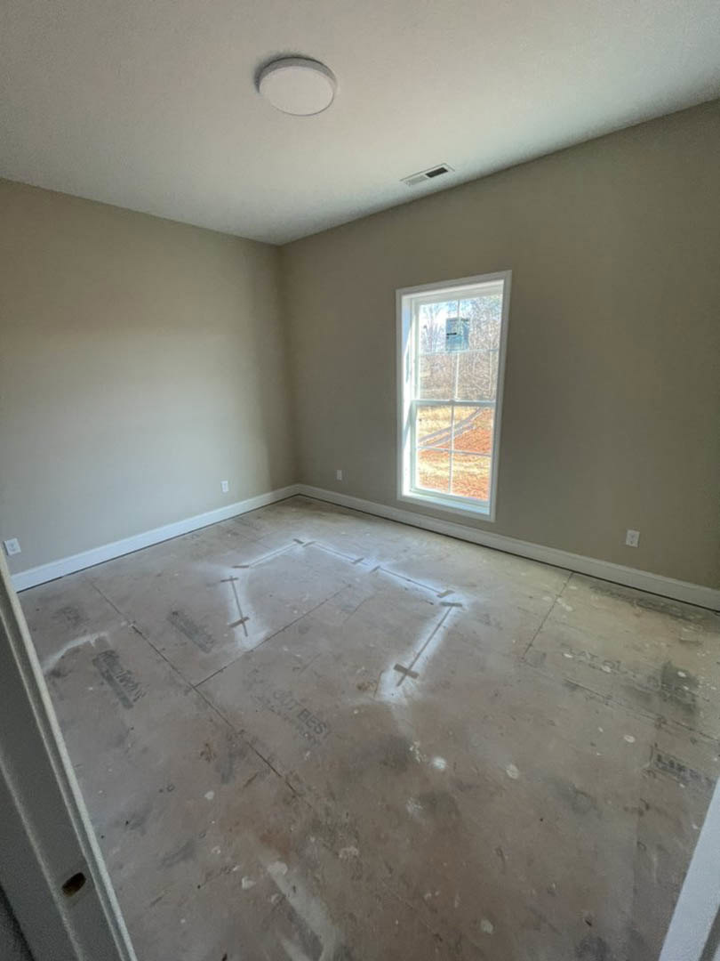 Sunlit room featuring a large window, smooth concrete flooring, white plaster walls, and a circular ceiling light fixture.