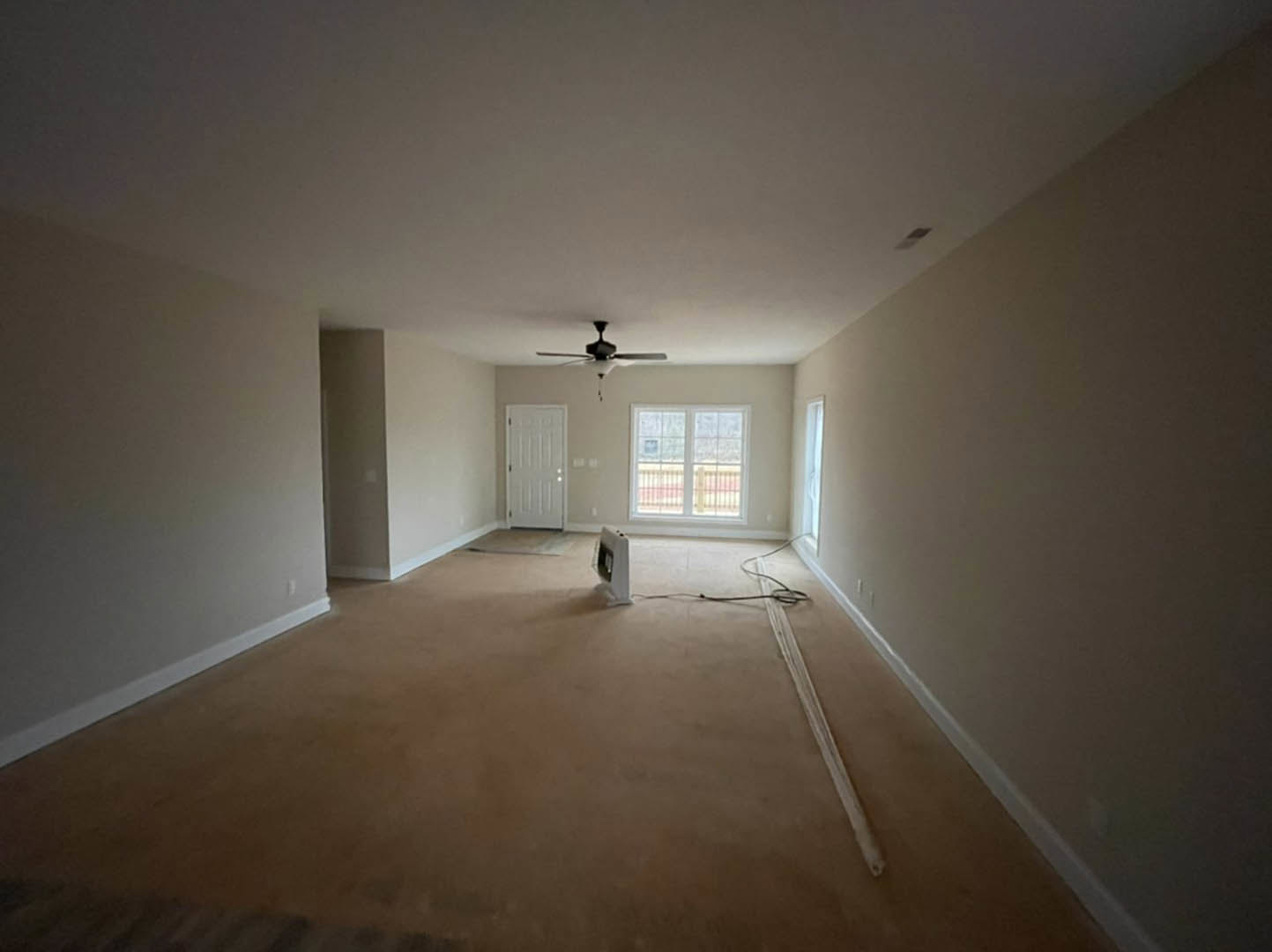 Bedroom with laminate flooring, white walls, ceiling fan with light fixture, large window with metal railing, and white door featuring a black handle