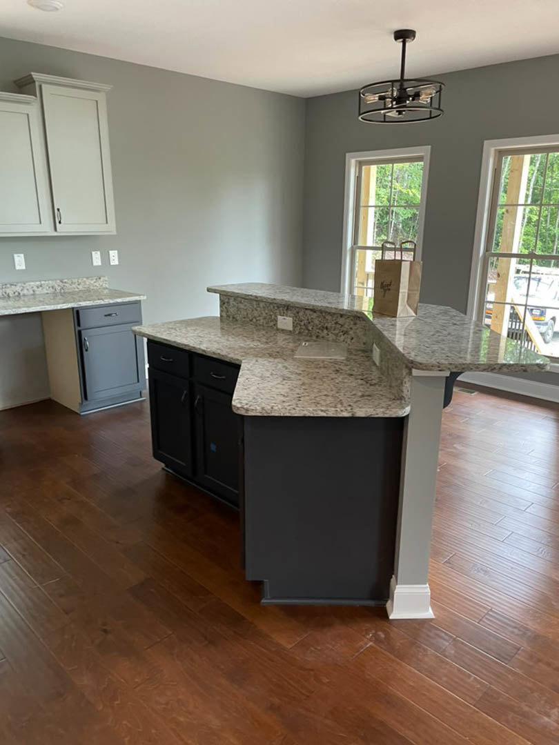 Kitchen with granite countertops, wood flooring, white cabinetry, stainless steel sink, ceiling light fixture, and a white door with metal handle