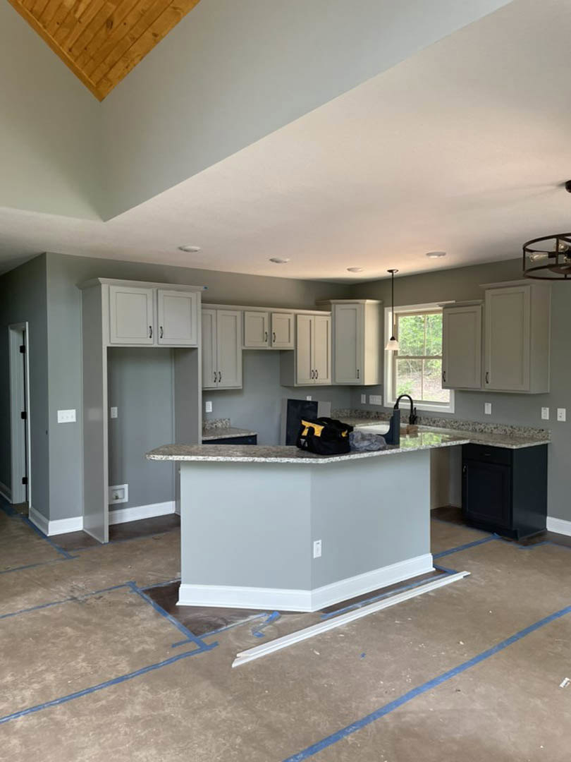 Marble countertop with black cabinetry, wood paneling corner, wall trim, and a black and yellow bag in a modern kitchen