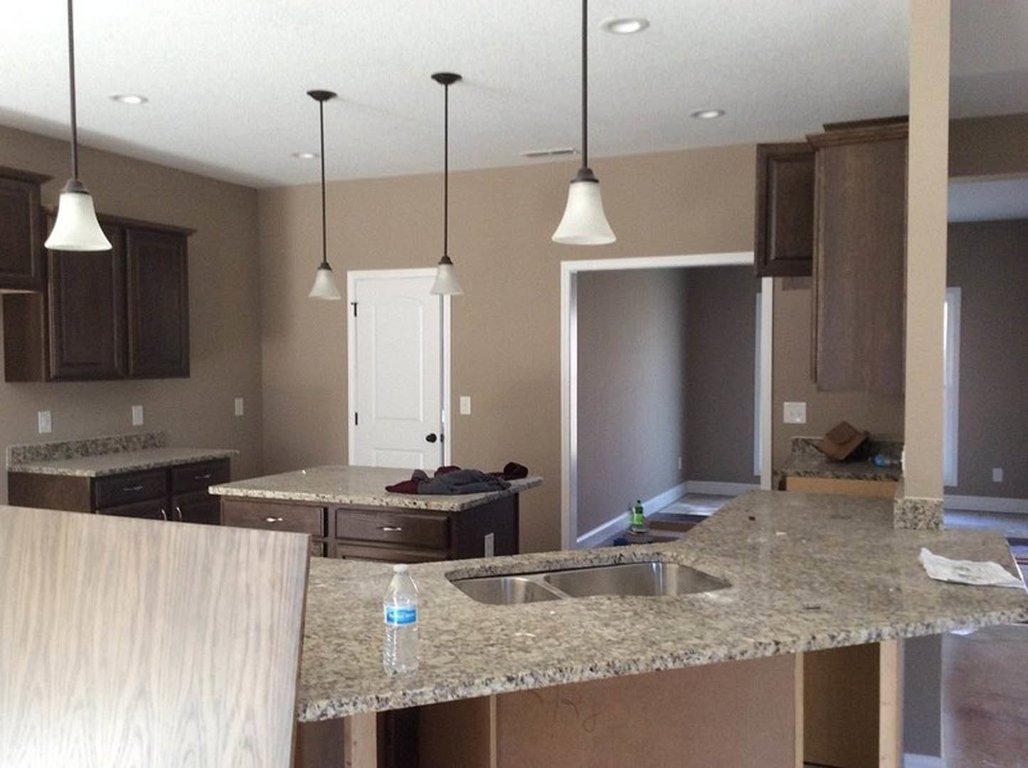 Modern kitchen featuring a quartz countertop with undermount sink, white cabinetry, stainless steel faucet, and a white door with black hinges in the background
