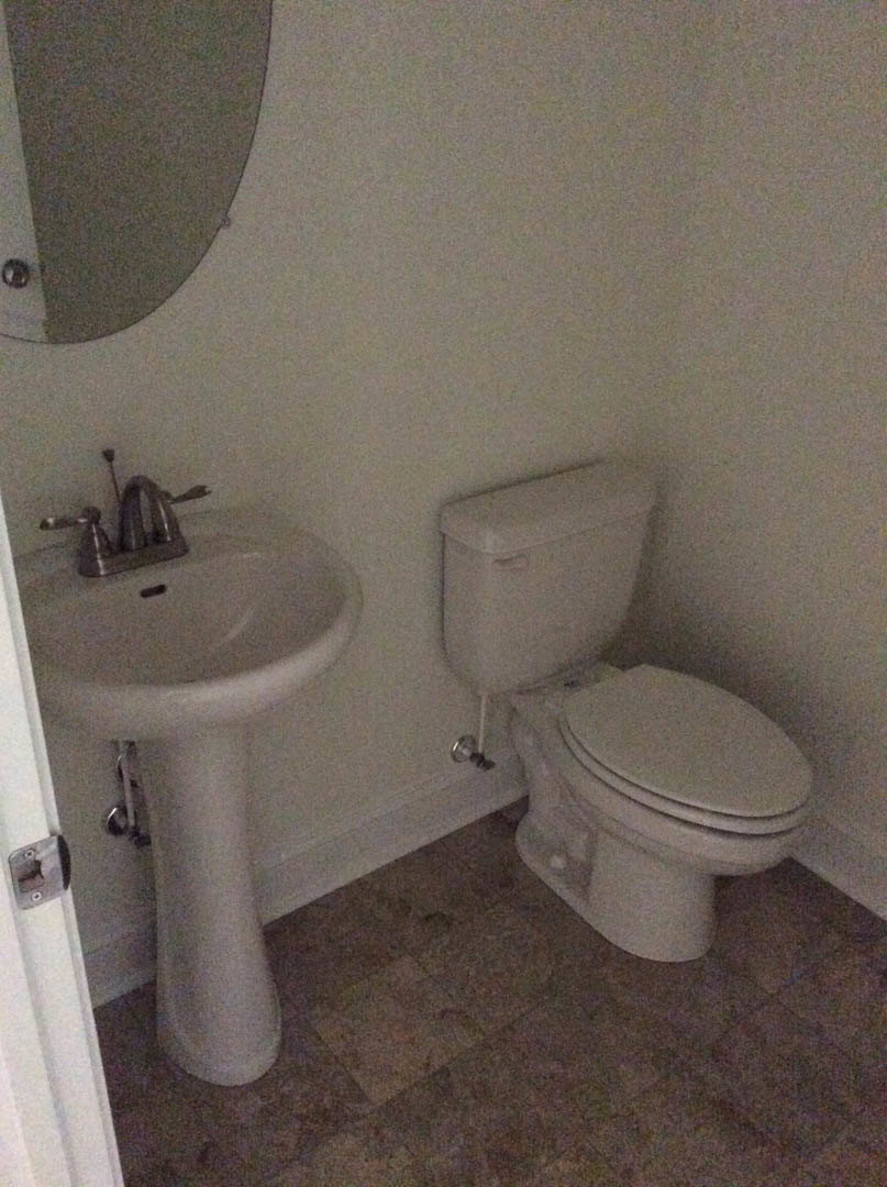 White porcelain toilet and rectangular sink with chrome faucet set against light tile walls and floor in a modern bathroom