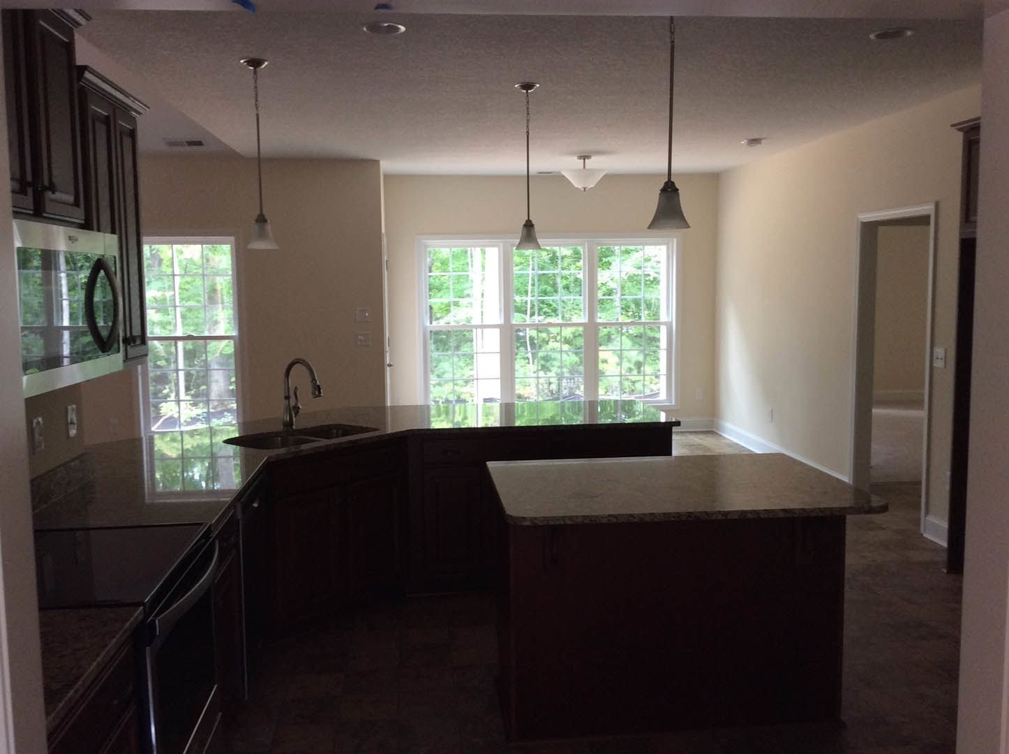 Modern kitchen featuring a wide picture window, white quartz countertops with black accent lines, stainless steel faucet, light wood cabinetry, and neutral tile flooring.