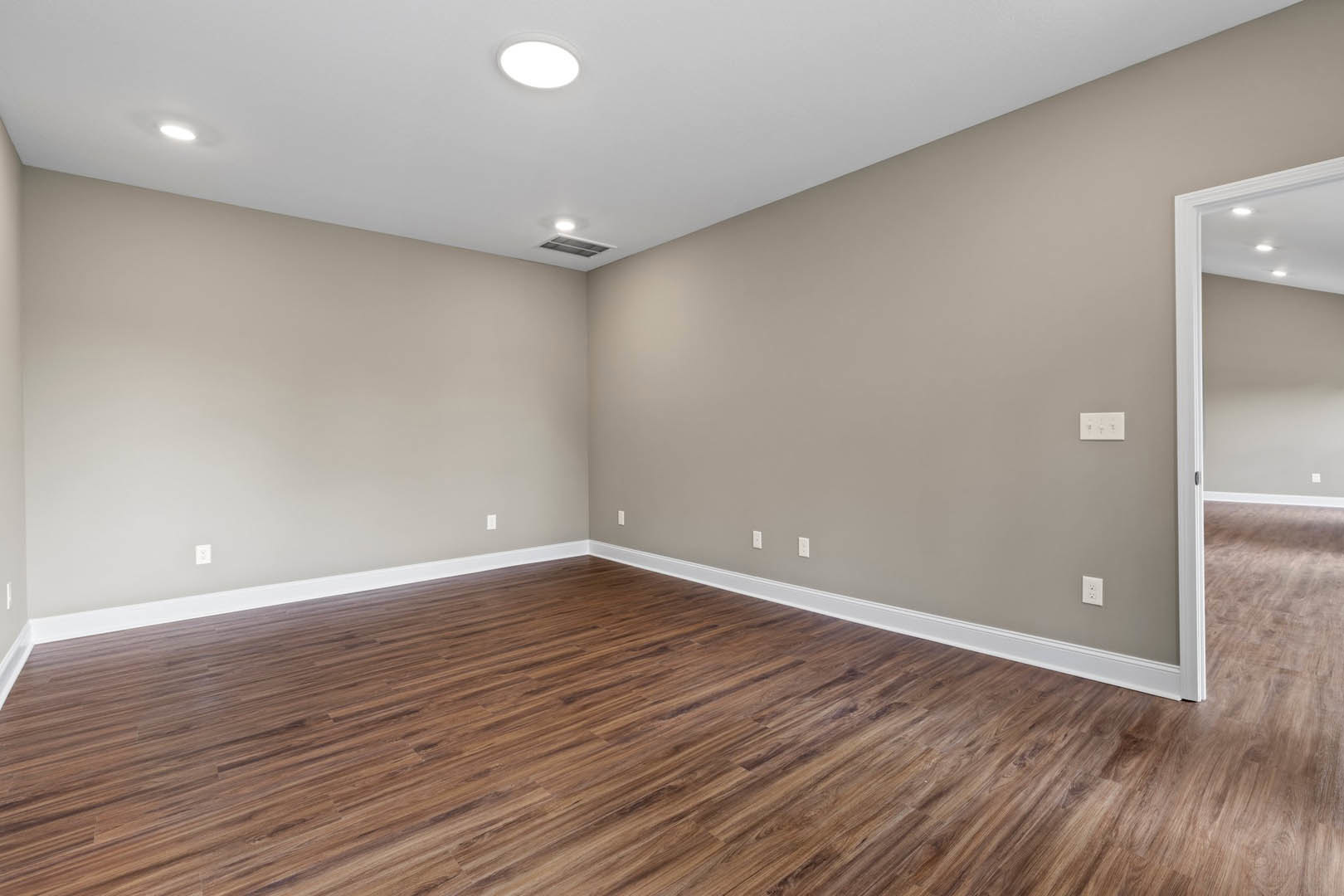 Wood flooring with white baseboards, white walls, recessed ceiling light, and a white light switch on the wall