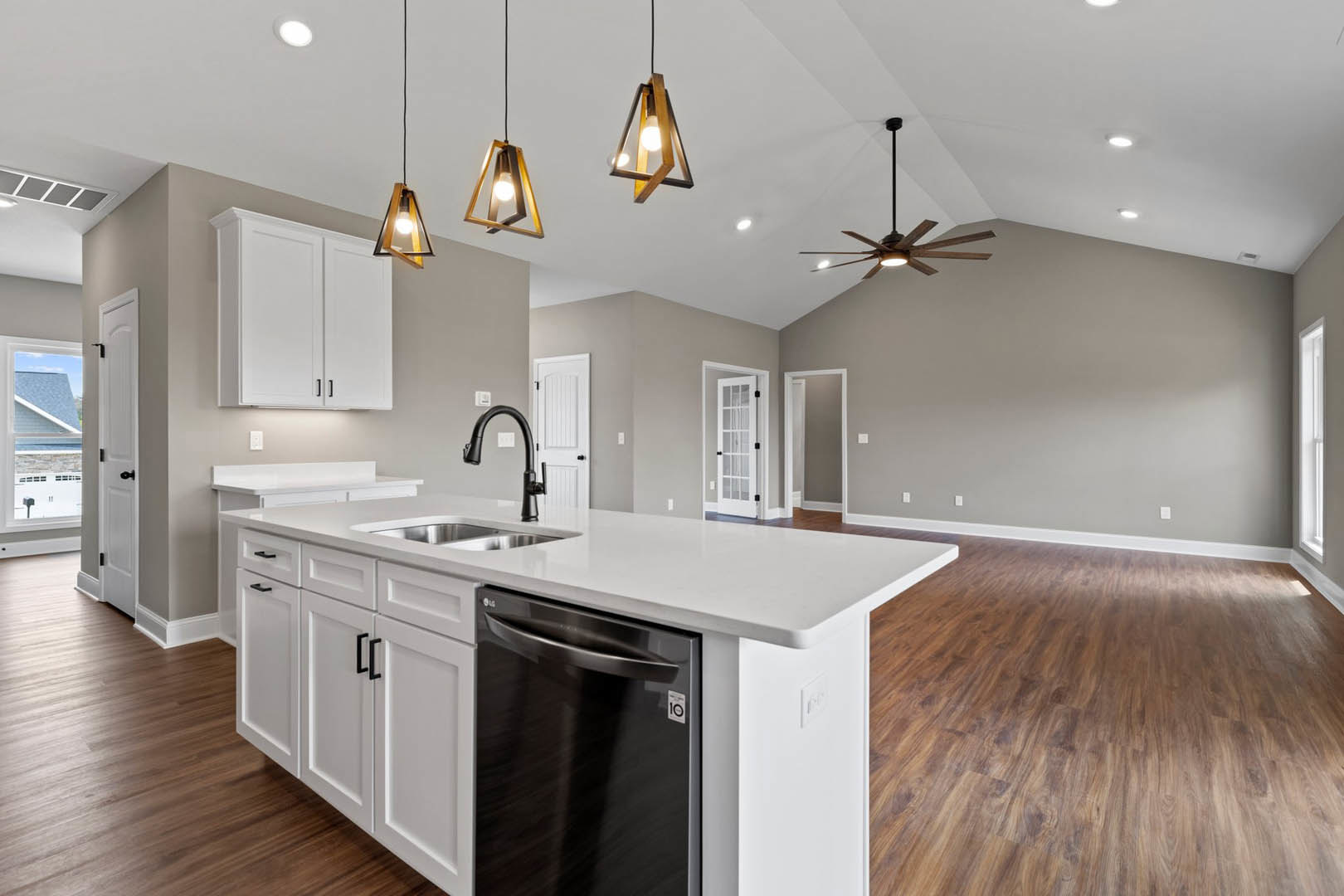 Kitchen with black dishwasher, wood flooring, white cabinets with black handles, triangle-shaped light fixture, and glass-paneled door