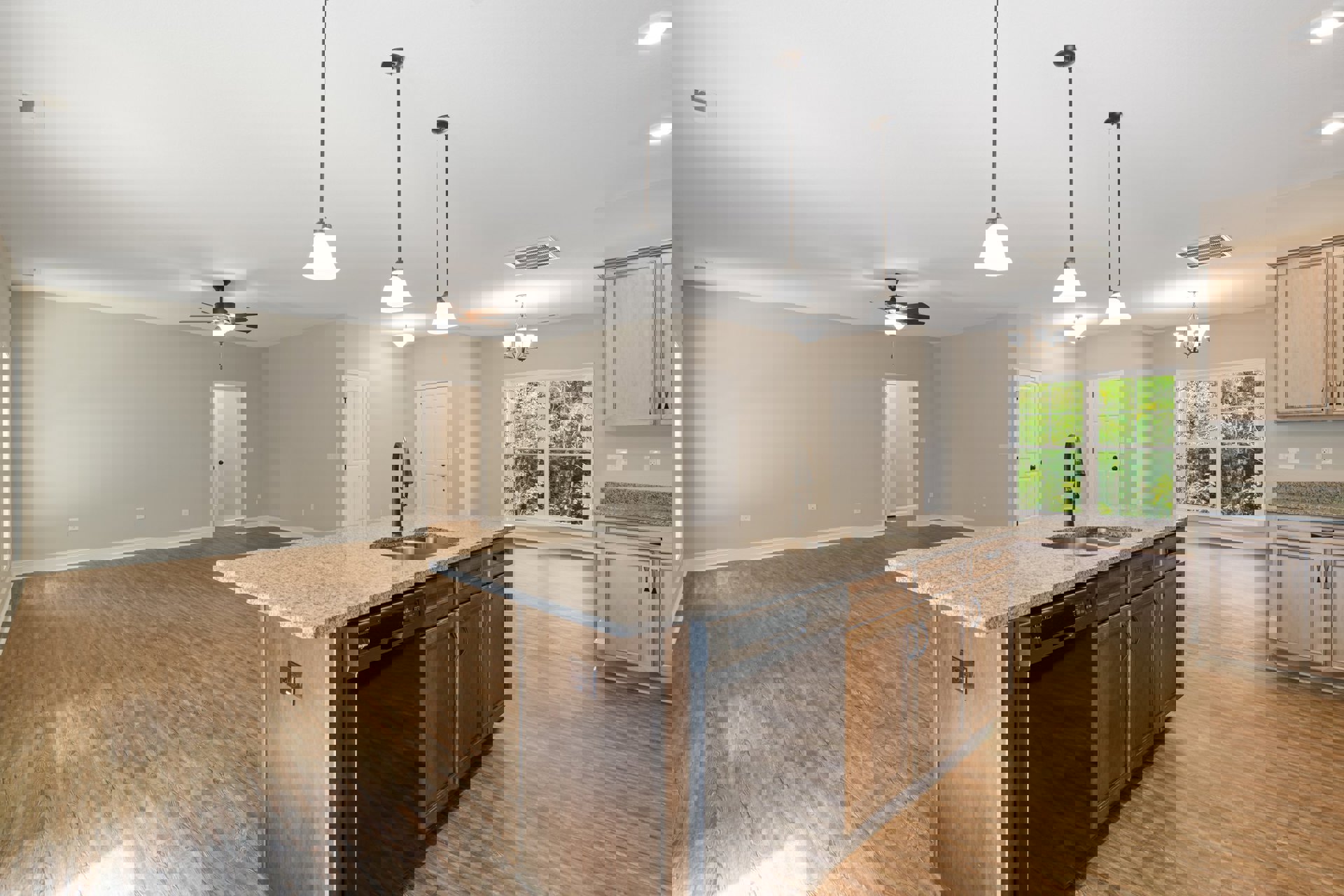 Quartz kitchen island with built-in sink and dishwasher, white cabinetry, wood flooring, large window overlooking trees, stainless steel appliances, pendant lighting above island