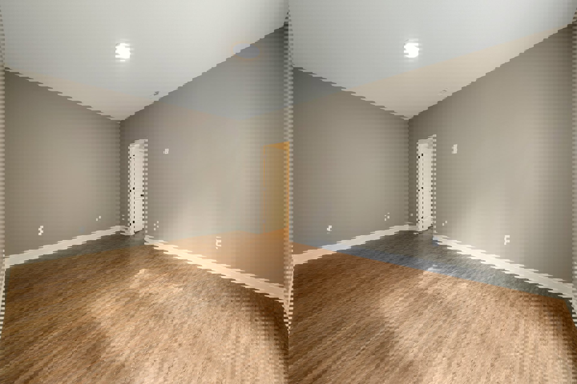 White paneled door with black knobs open to a room featuring hardwood floors, light gray walls, and recessed ceiling light.