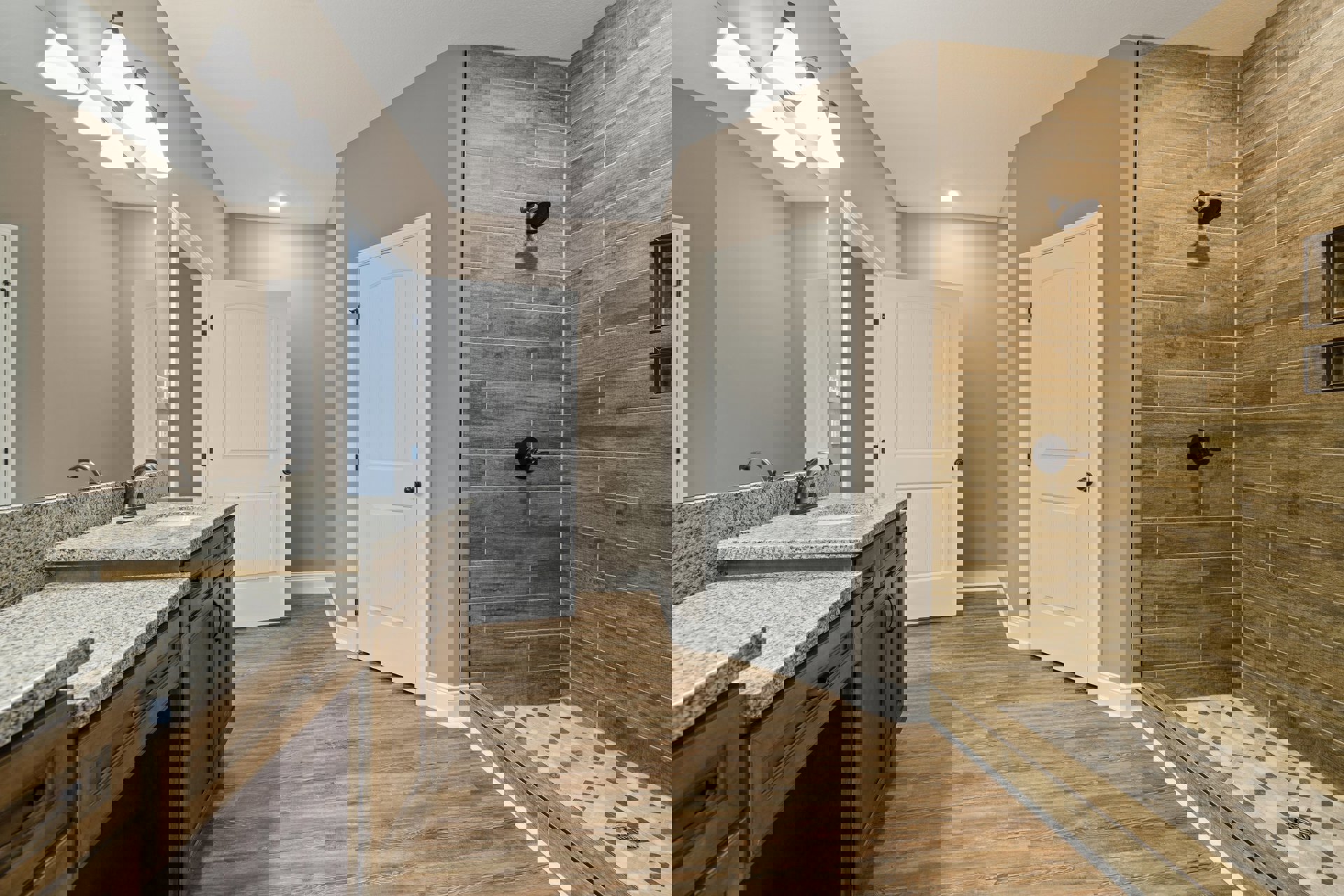 Bathroom with glass-enclosed shower, marble countertop double sink vanity, white cabinetry, black hardware, tile flooring, and modern light fixture.