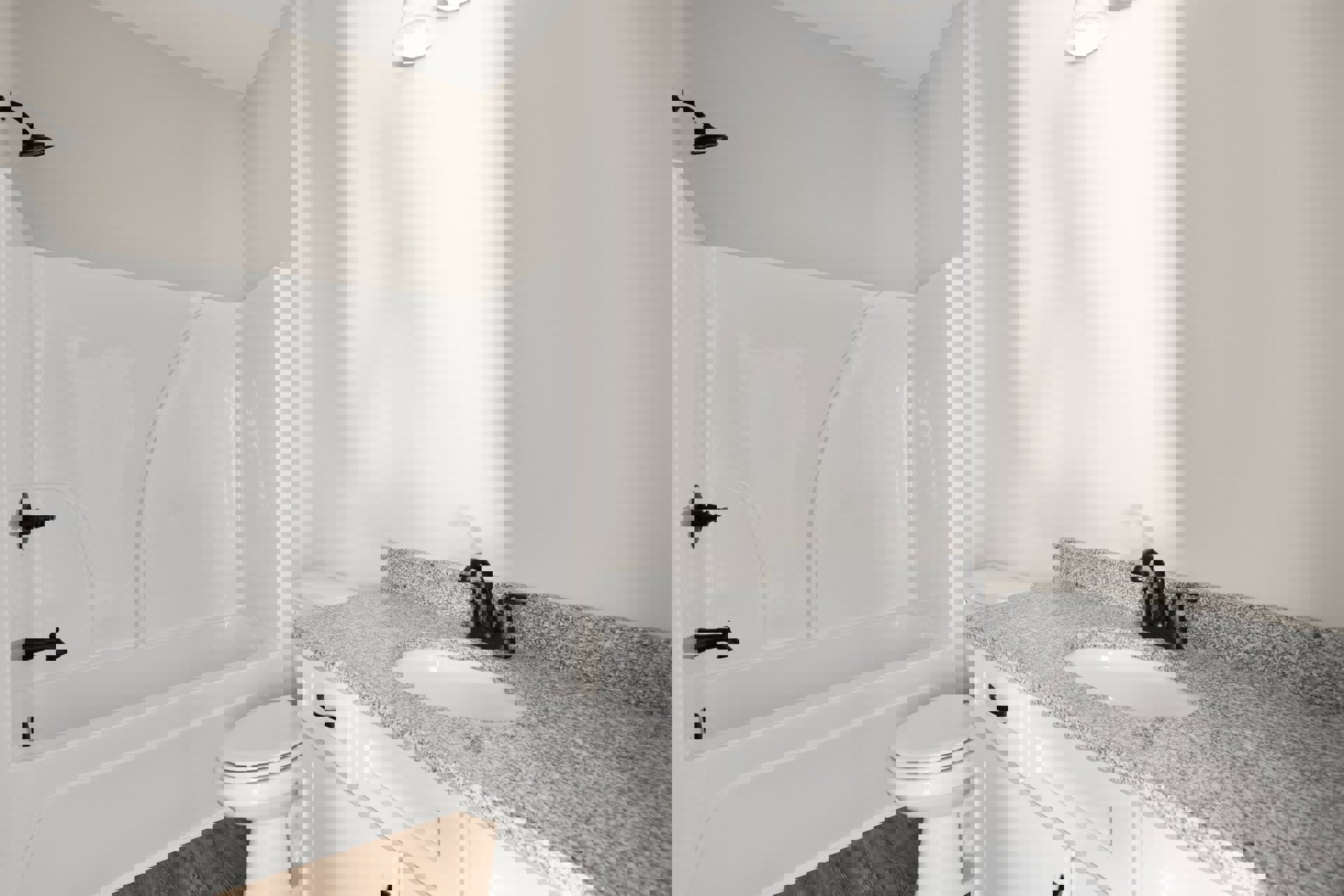 Modern bathroom featuring a freestanding white bathtub, white toilet with closed lid, wall-mounted shower head, rectangular sink with chrome faucet set on a stone countertop, and