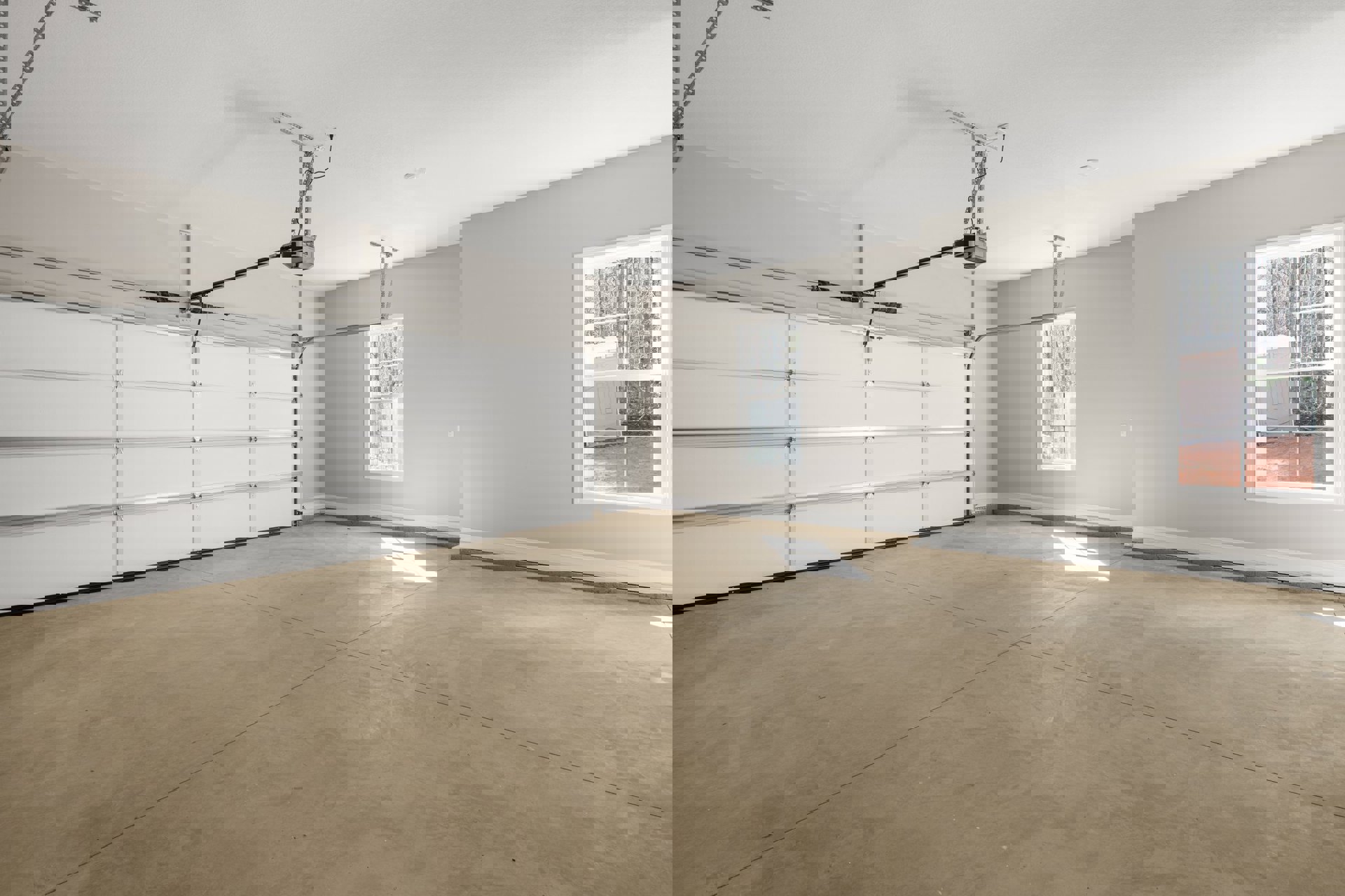 Garage interior with white tile floor, plaster walls, ceiling-mounted wire, wall light fixture, and window framed in white showing trees outside