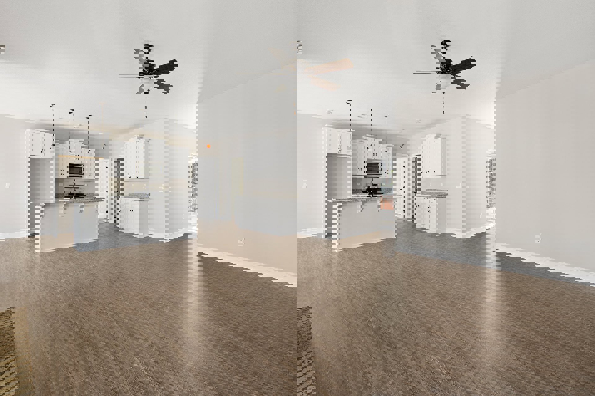 Spacious open floor plan featuring hardwood flooring, white kitchen cabinetry with black handles, sleek countertops, ceiling fan with light fixture, and adjacent dining area