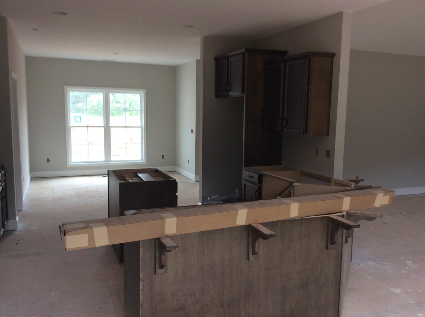 Bright kitchen with multi-pane window, wood cabinets, open shelving, stone countertop, and hardwood flooring