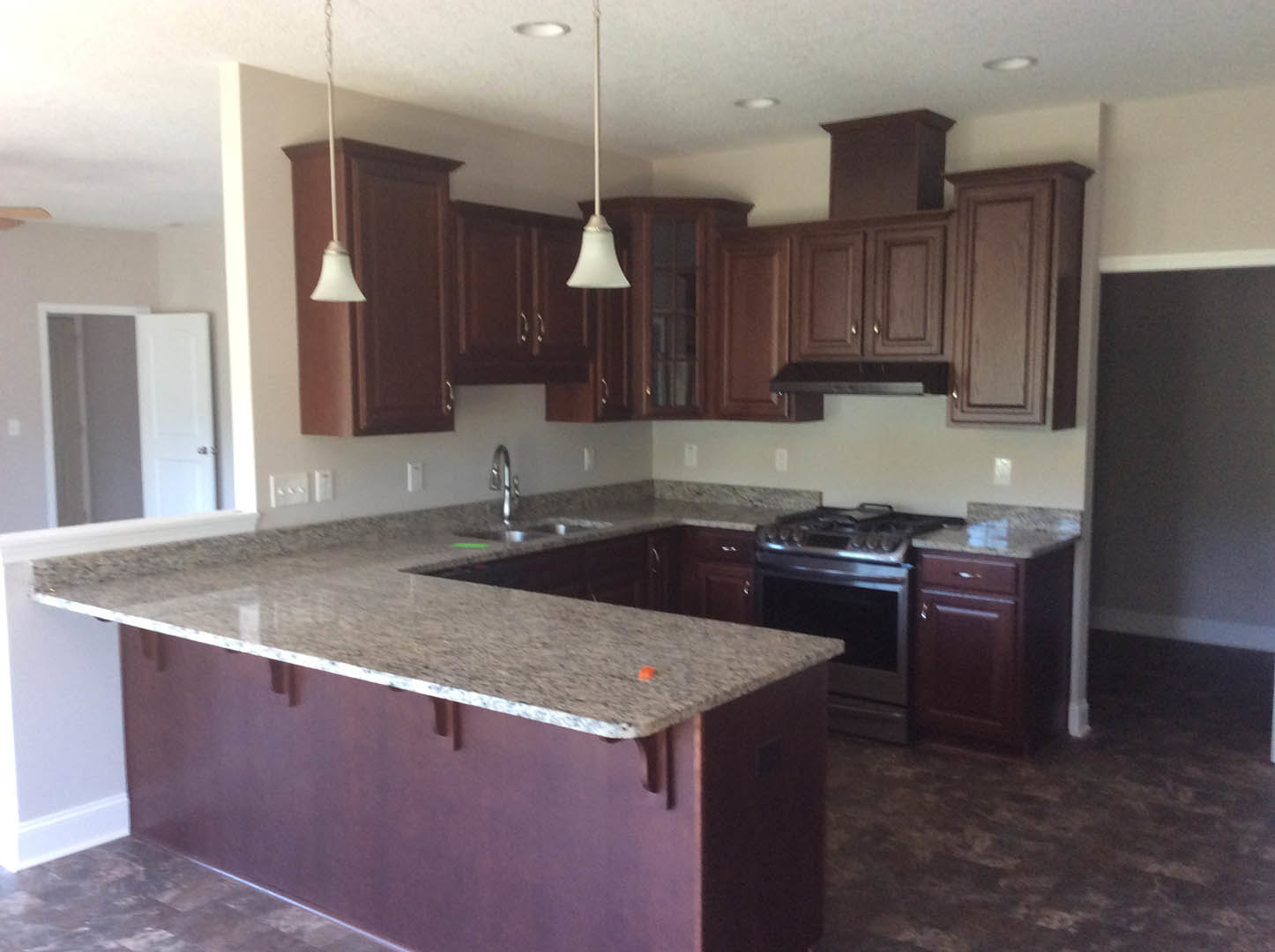 Granite countertop kitchen with tile flooring, white cabinetry, stainless steel stove and oven, undermount sink, and neutral wall finishes