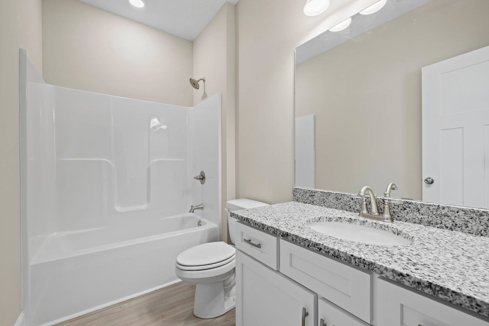 Marble countertop with undermount sink, freestanding white bathtub, white toilet, tiled walls, chrome shower head, white door