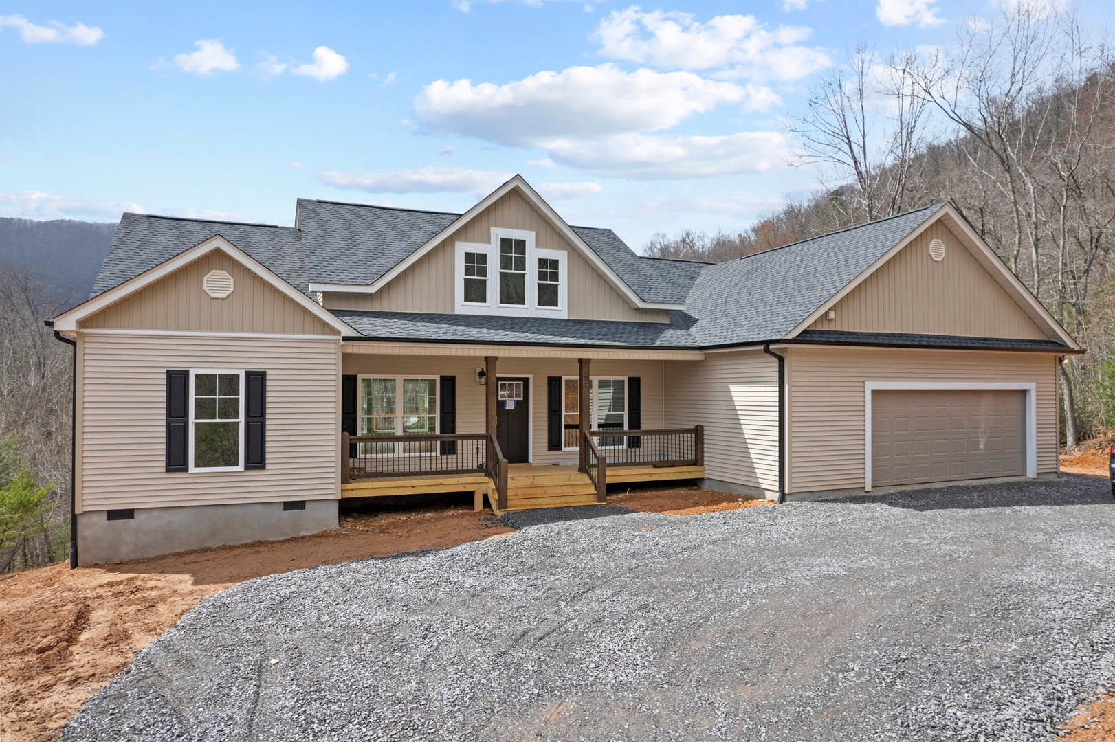 Two-story house with white siding, black shuttered windows, covered porch, gravel driveway, and wooden deck.