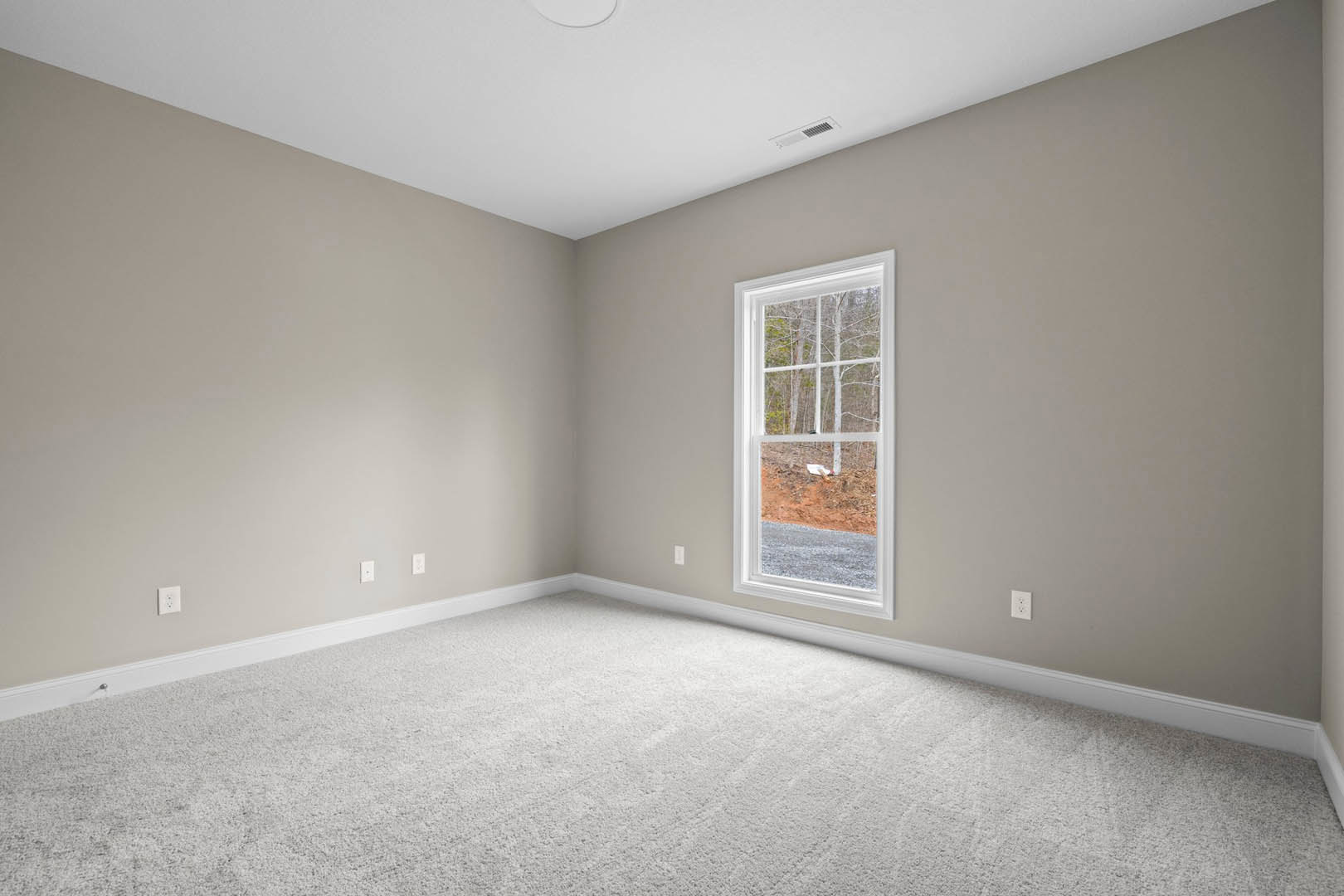 Bright room with white carpet, large window overlooking forest, white ceiling with circular light fixture, white walls, small white object on floor.