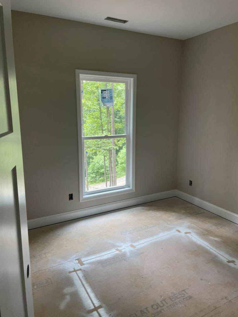 Concrete floor with large window overlooking trees, plaster walls, and ceiling in a bright indoor space