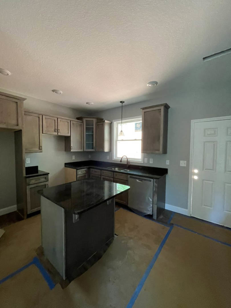 Modern kitchen featuring matte black countertop, white cabinetry, stainless steel appliances, light wood flooring, and recessed ceiling lighting
