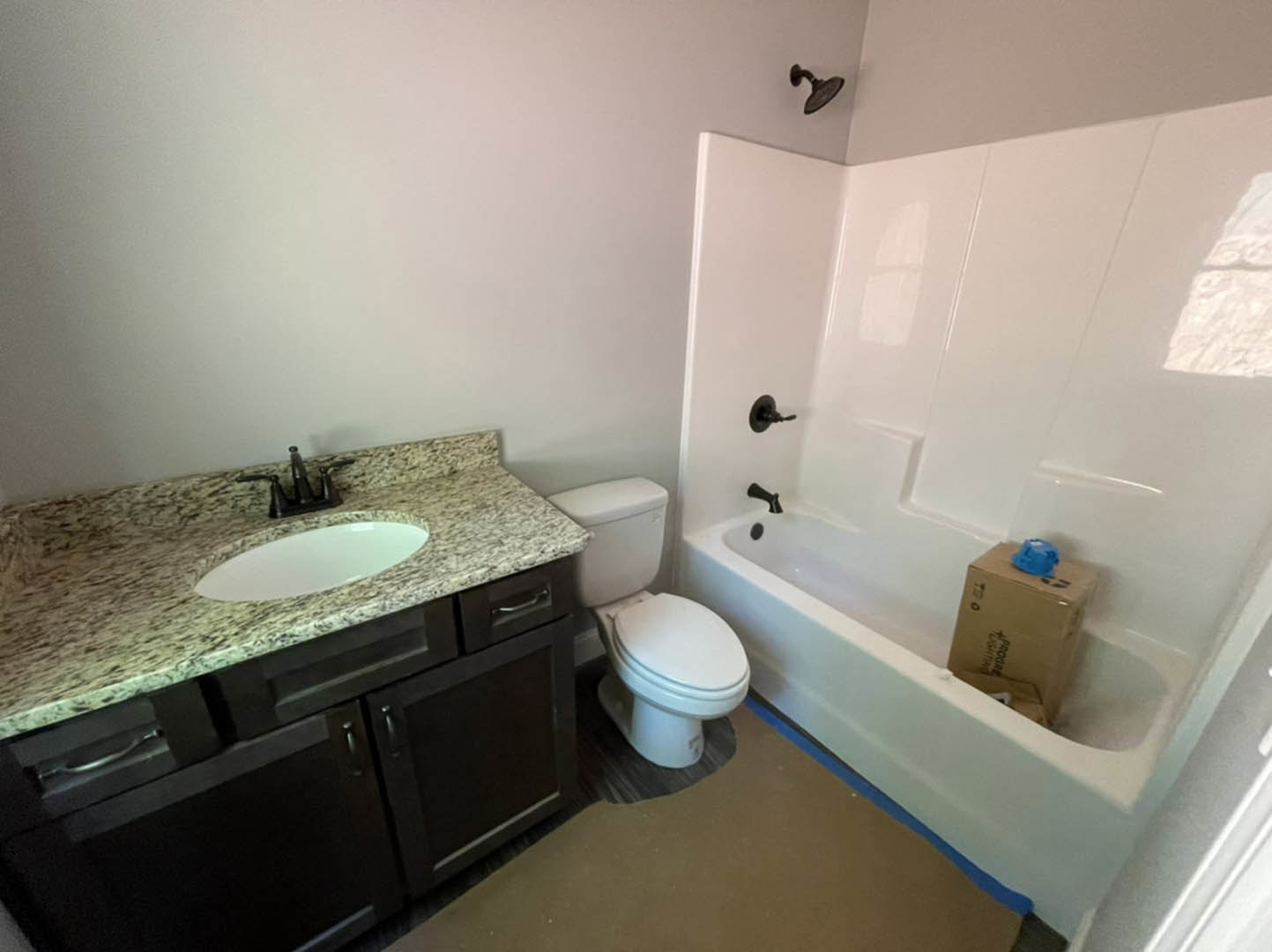 Modern bathroom featuring a freestanding bathtub, white countertop sink with chrome faucet, wall-mounted toilet, light gray tile flooring, and minimalist cabinetry
