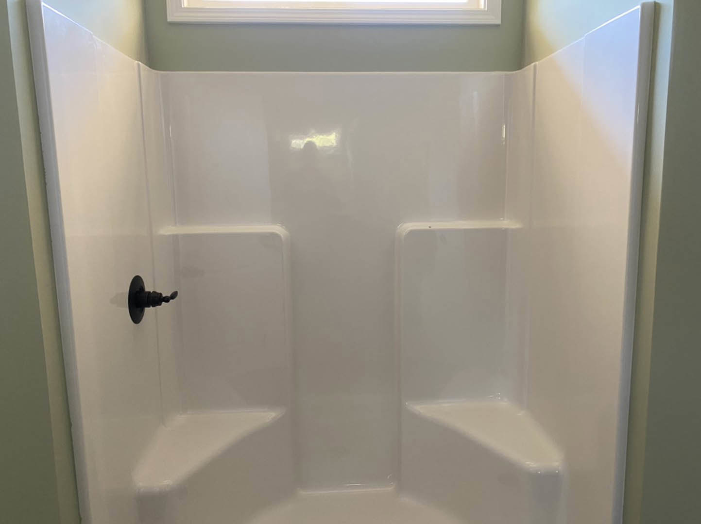 White tile shower with matte black wall-mounted faucet and spout