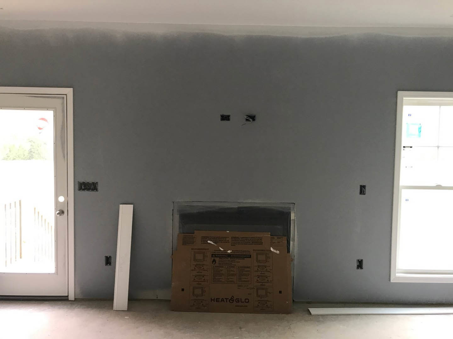 Living room with plaster walls, central fireplace with white mantel, two white doors, hardwood floor, and ceiling trim